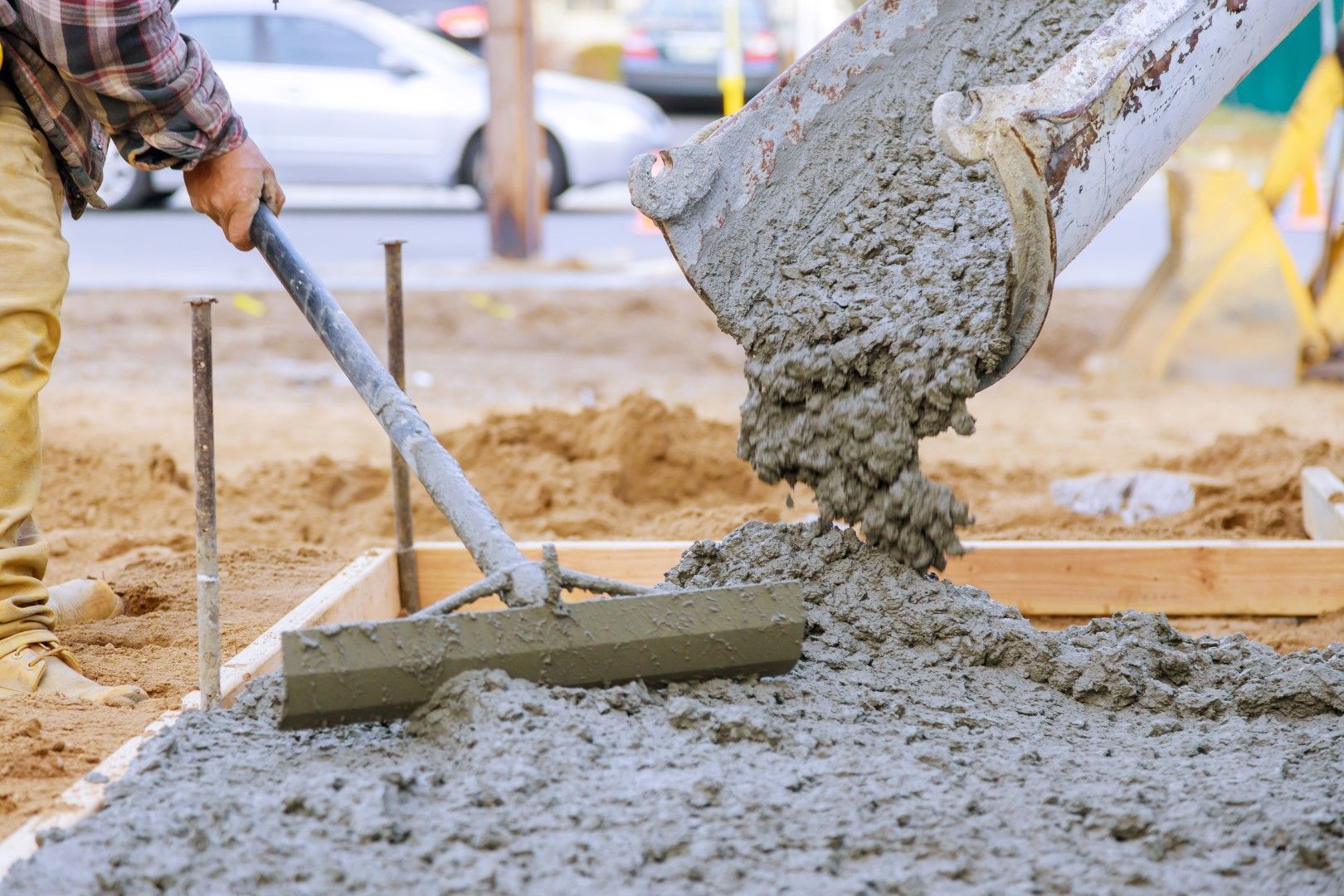 A man is spreading concrete with a shovel on a construction site.