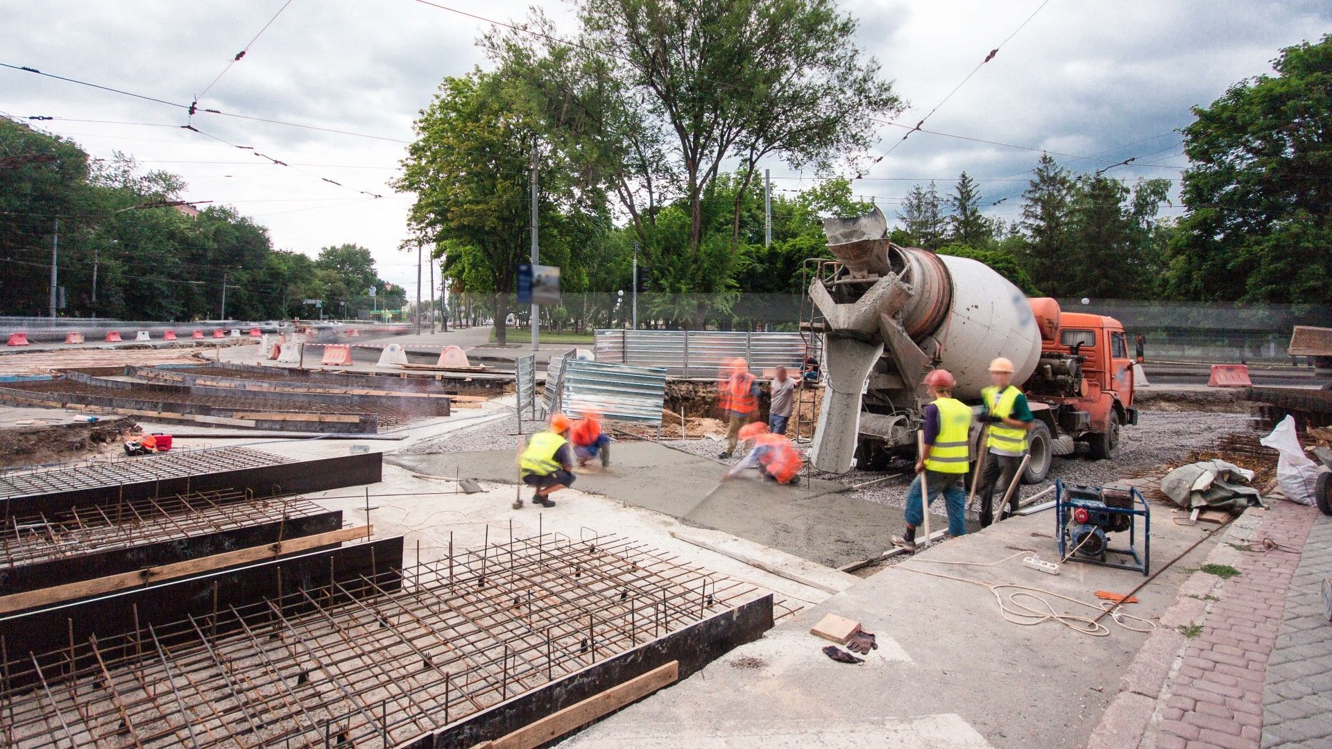 A group of construction workers are standing in front of a cement truck.