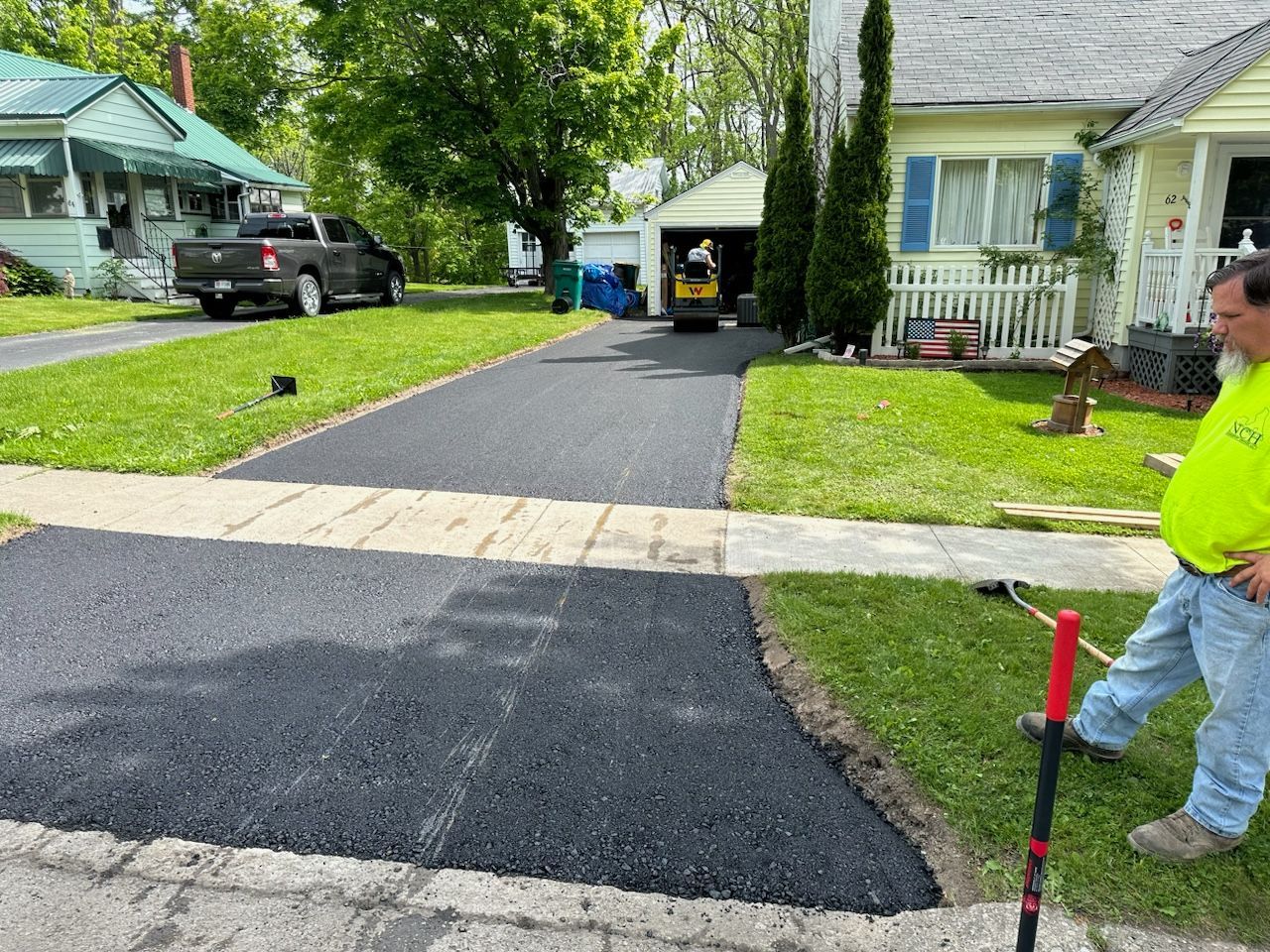 Freshly paved asphalt driveway with worker in neon shirt.