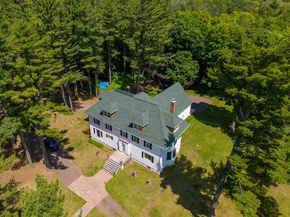 An aerial view of a large white house surrounded by trees.