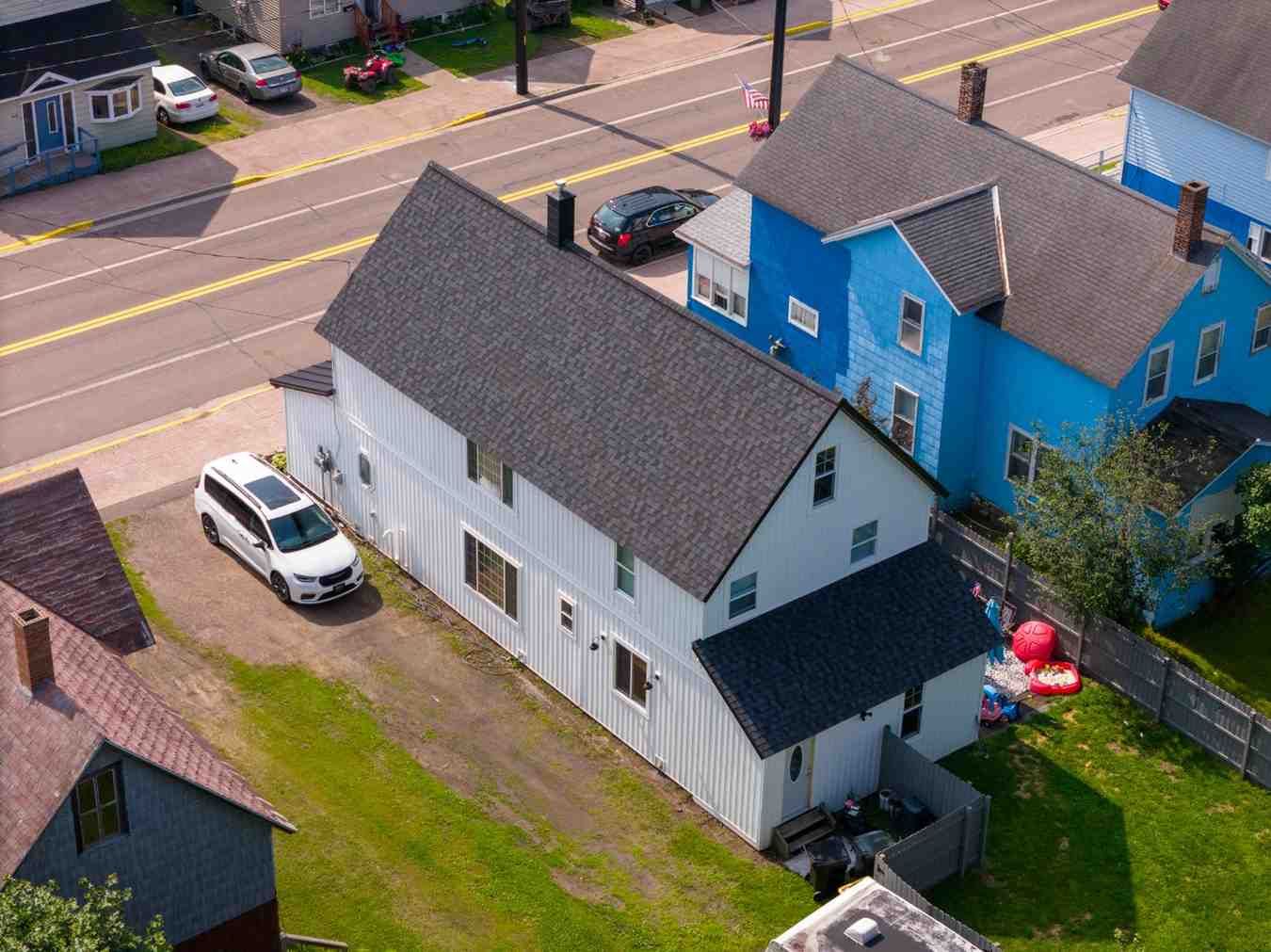An aerial view of a white house next to a blue house.