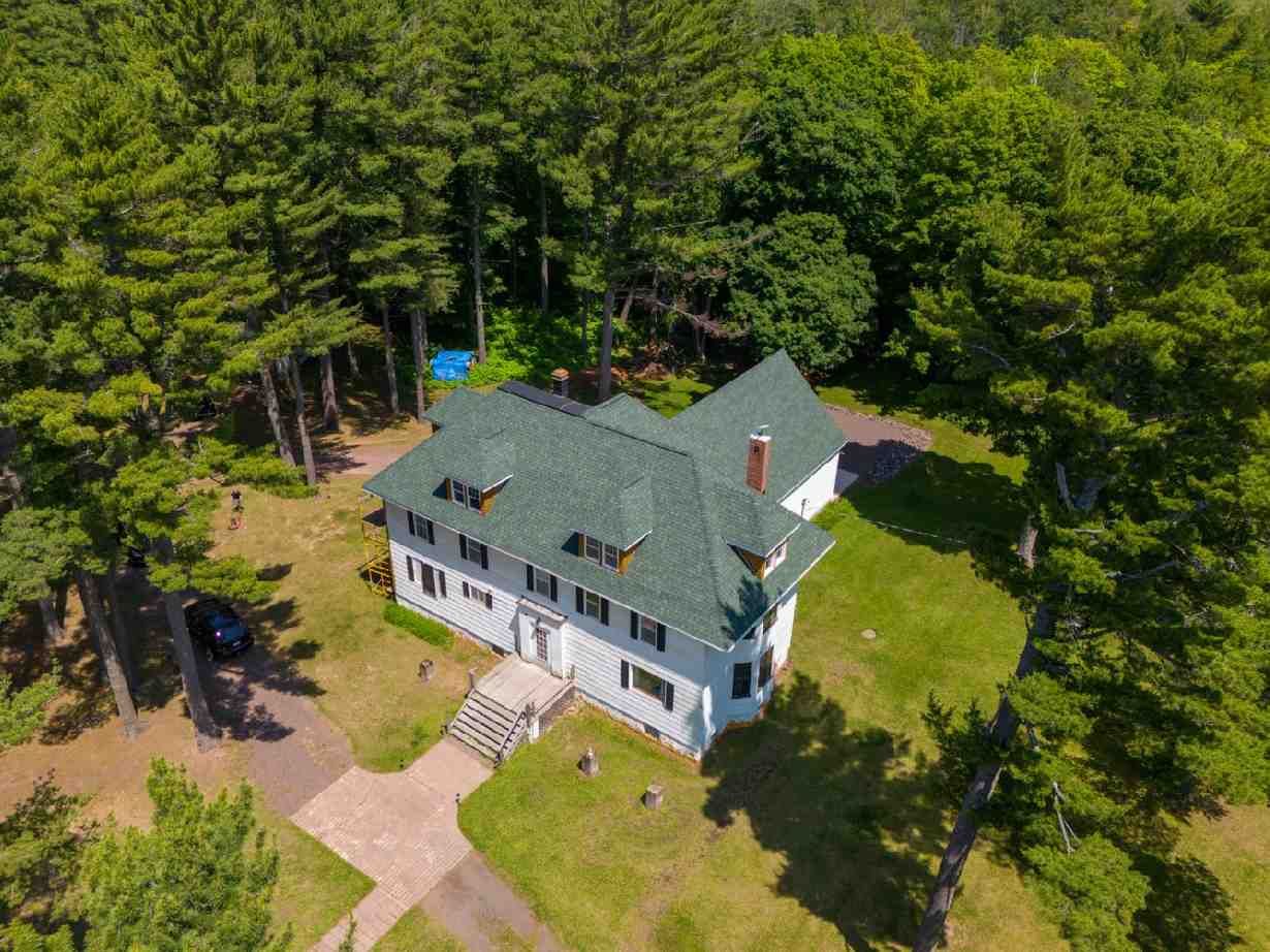 An aerial view of a large white house surrounded by trees.