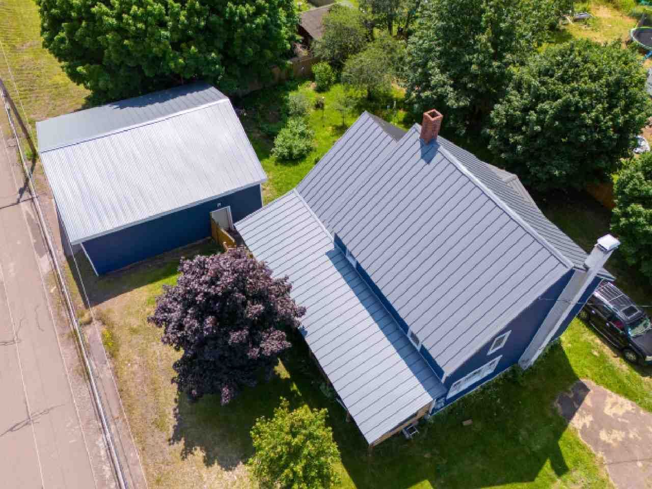 An aerial view of a house with a metal roof and a garage.