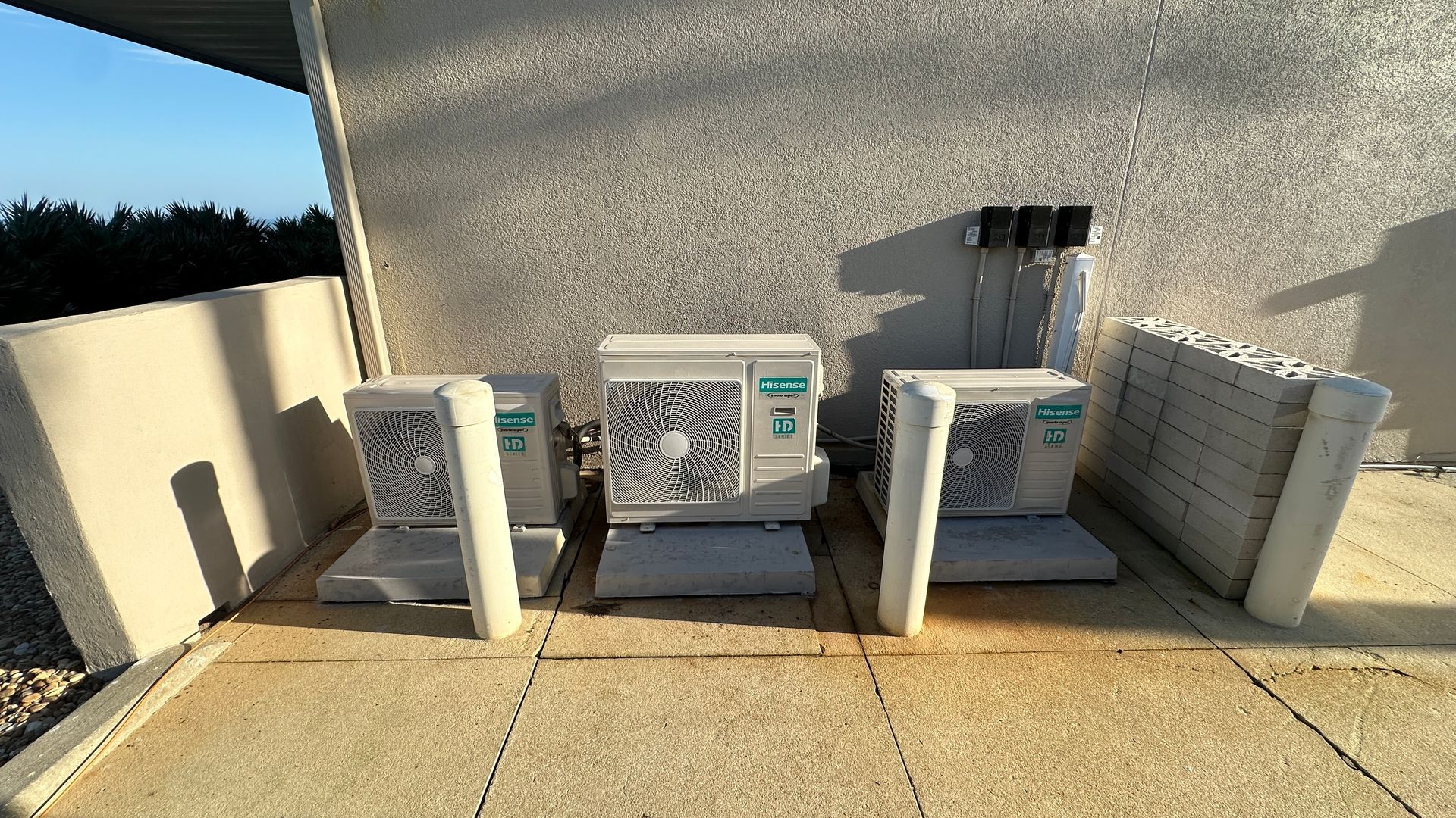 A large, gray industrial HVAC unit sits on a gravel rooftop under a clear blue sky, next to a satellite dish.