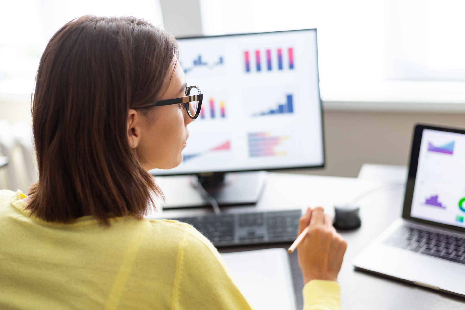 A woman is sitting at a desk looking at a computer screen.