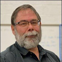 A man with a beard and glasses is smiling for the camera.