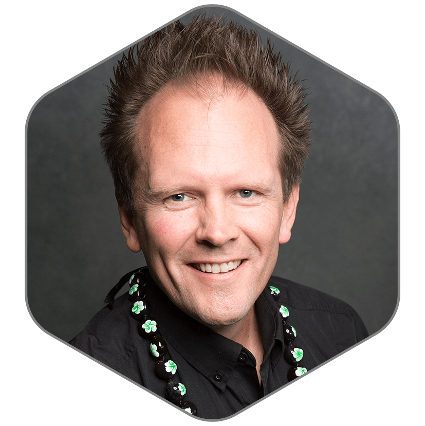 A man wearing a black shirt and a green necklace is smiling for the camera.