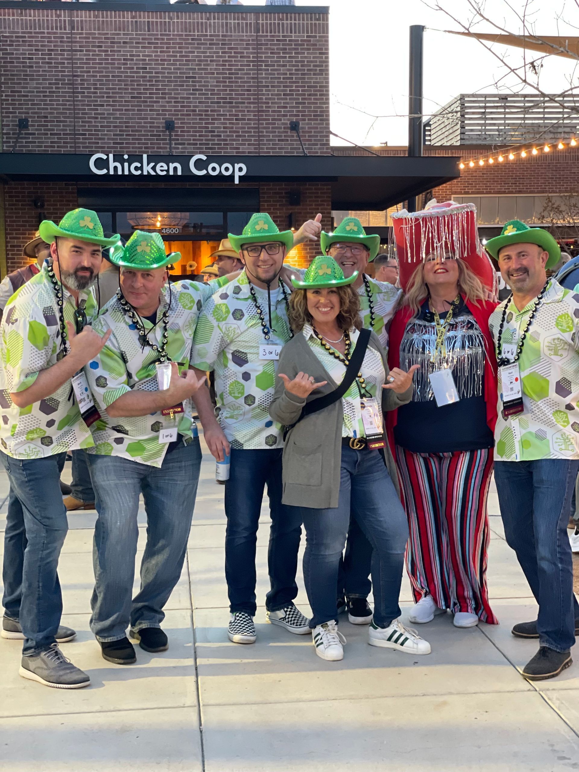 A group of people are posing for a picture in front of a chicken coop.