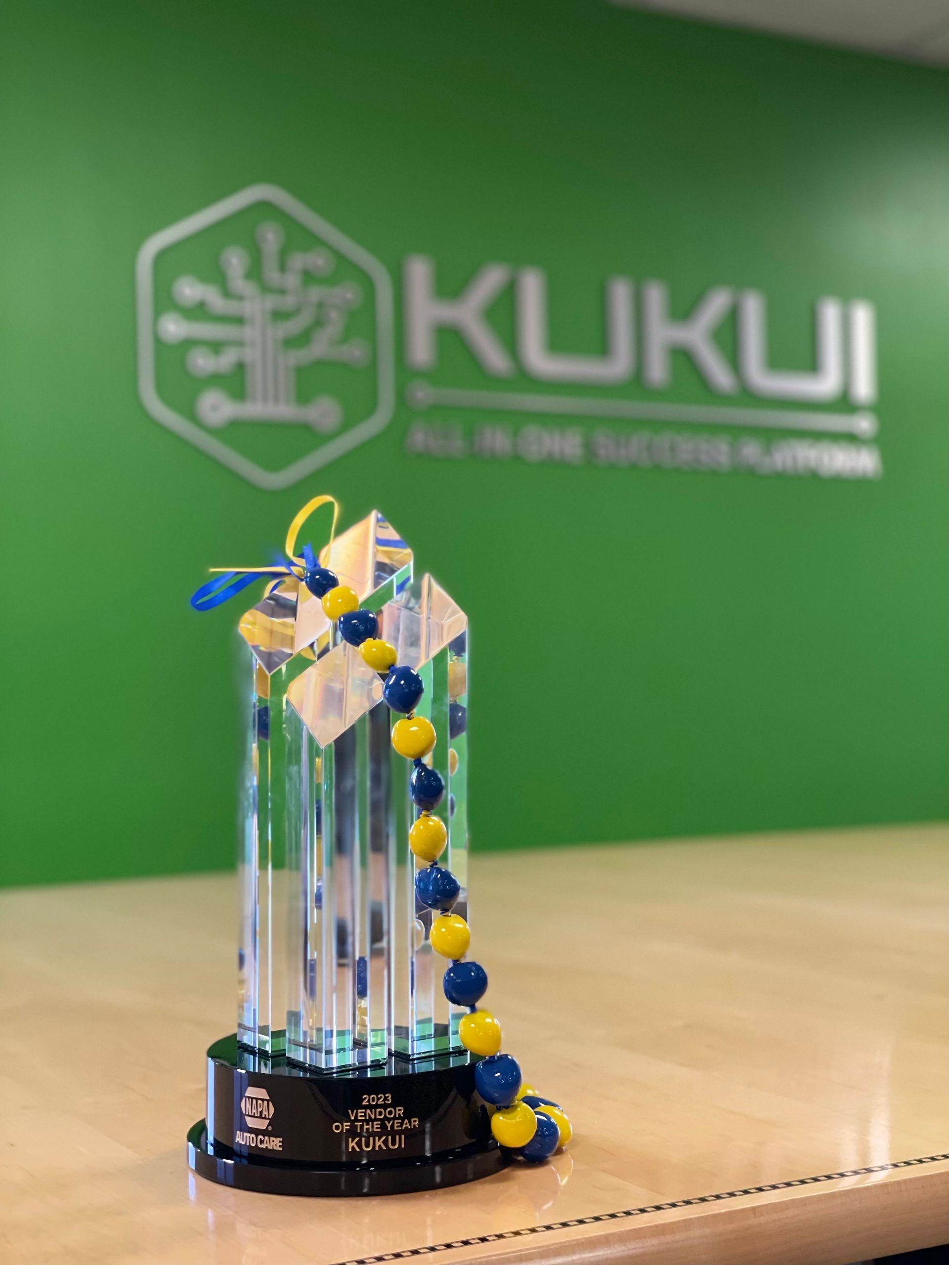 A trophy is sitting on a table in front of a kukui logo