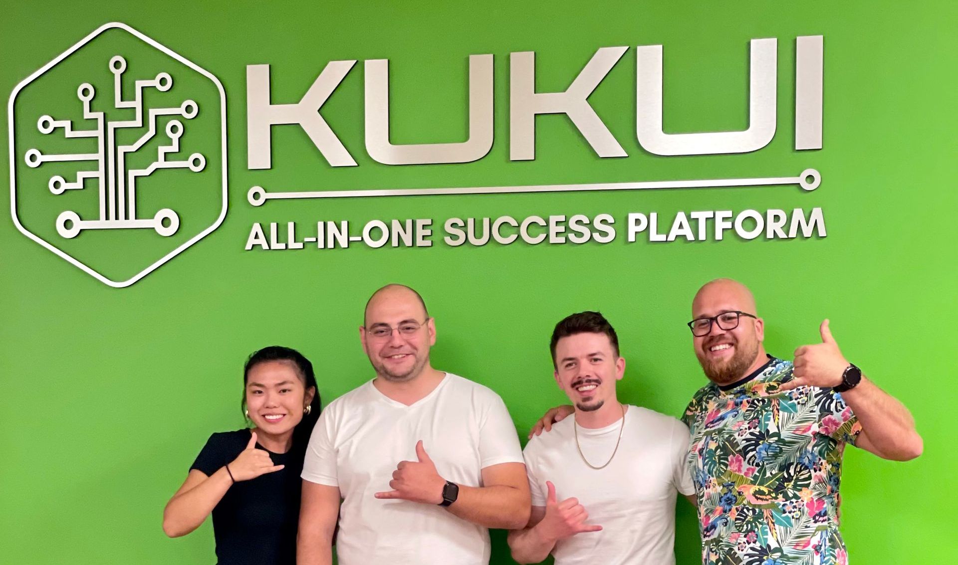 A group of people are posing for a picture in front of a green wall.