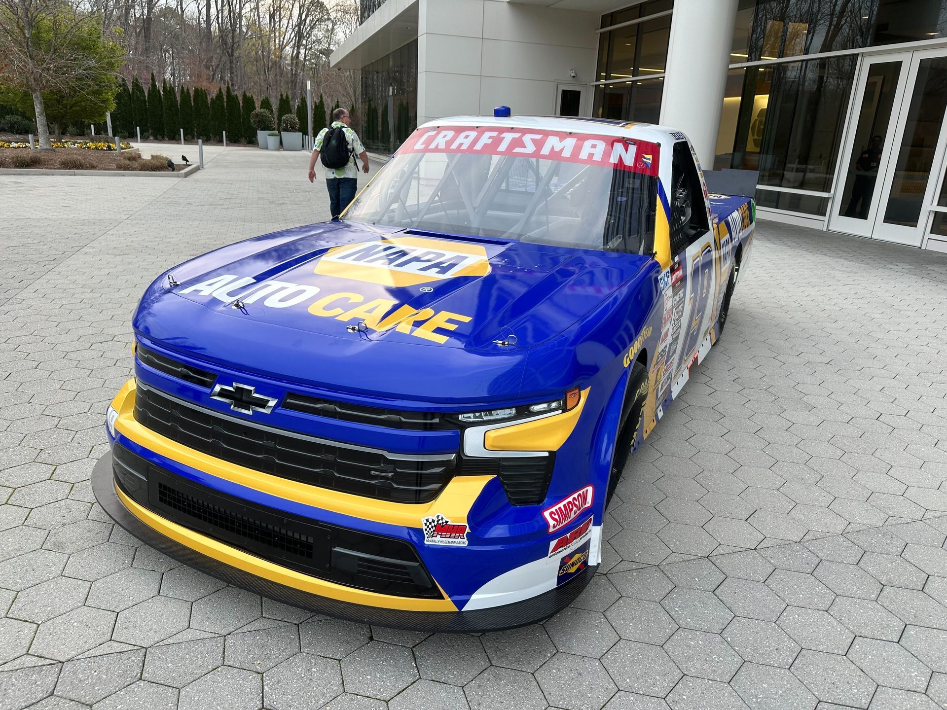 A blue and yellow race car is parked in front of a building.