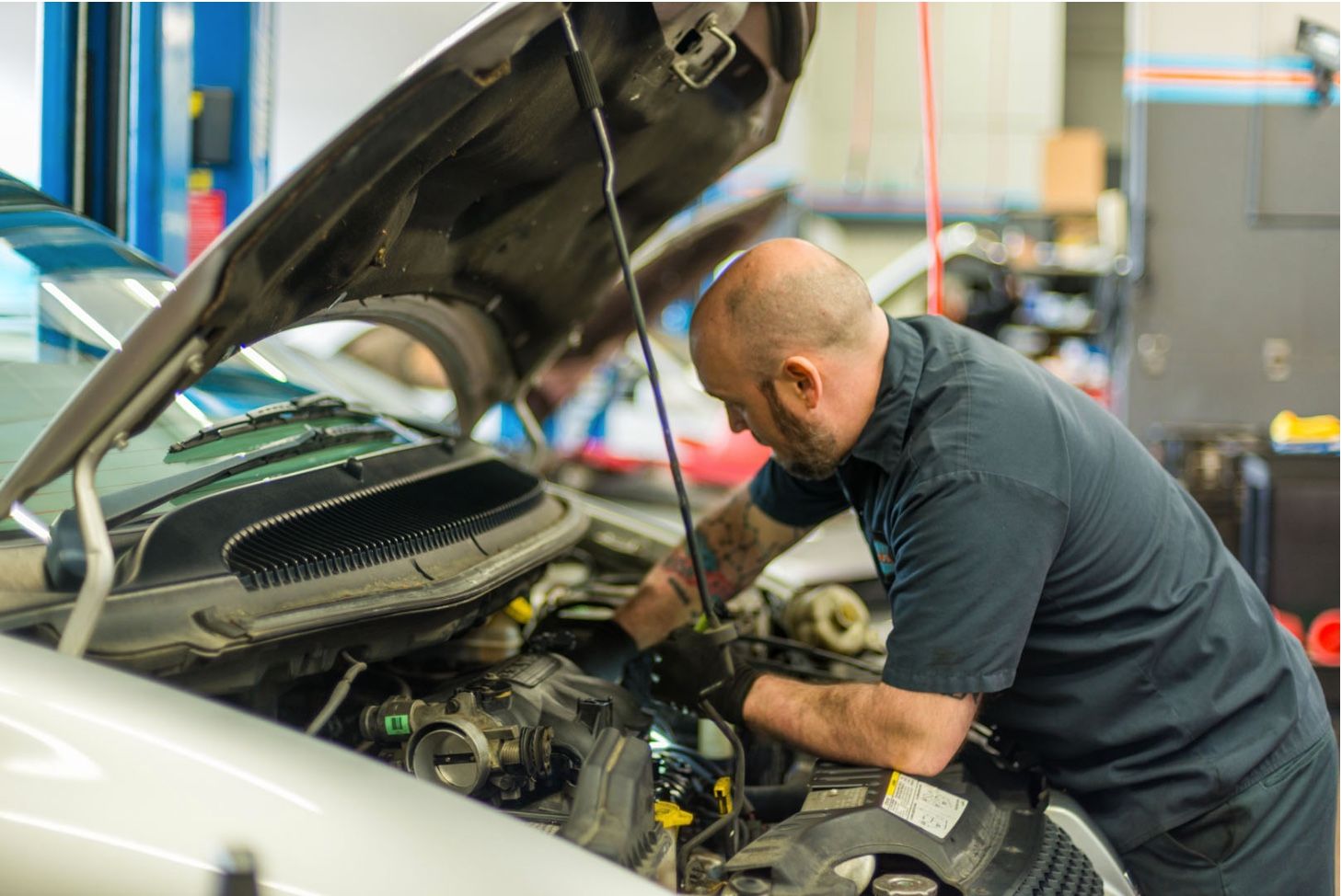 A man is working on the engine of a car in a garage.