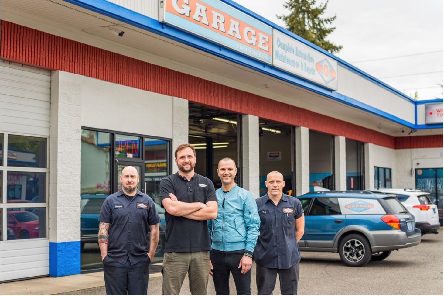 A group of men are standing in front of a garage.