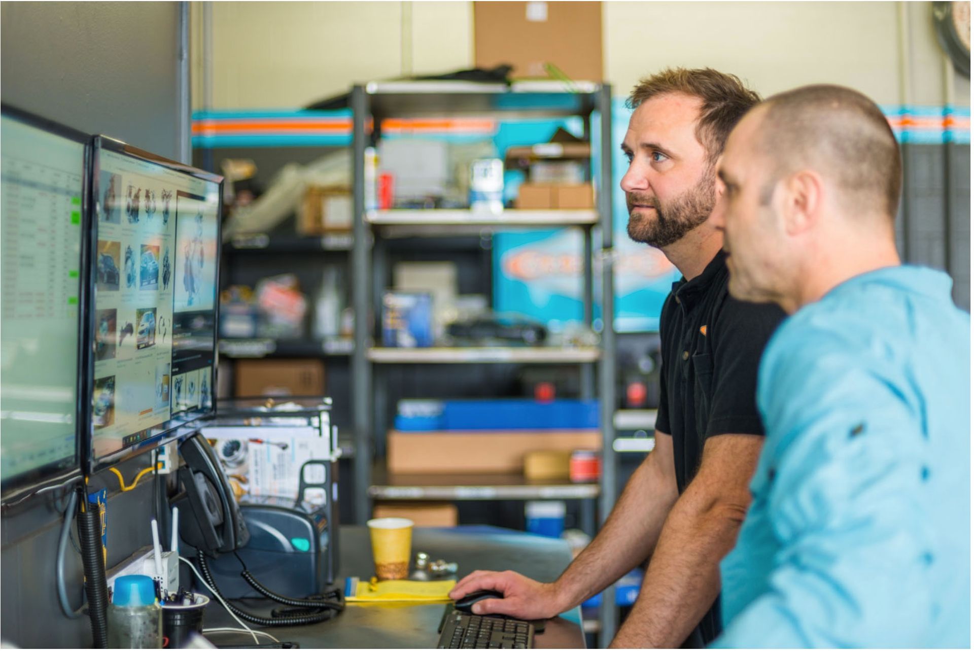 Two men are looking at a computer screen in a garage.
