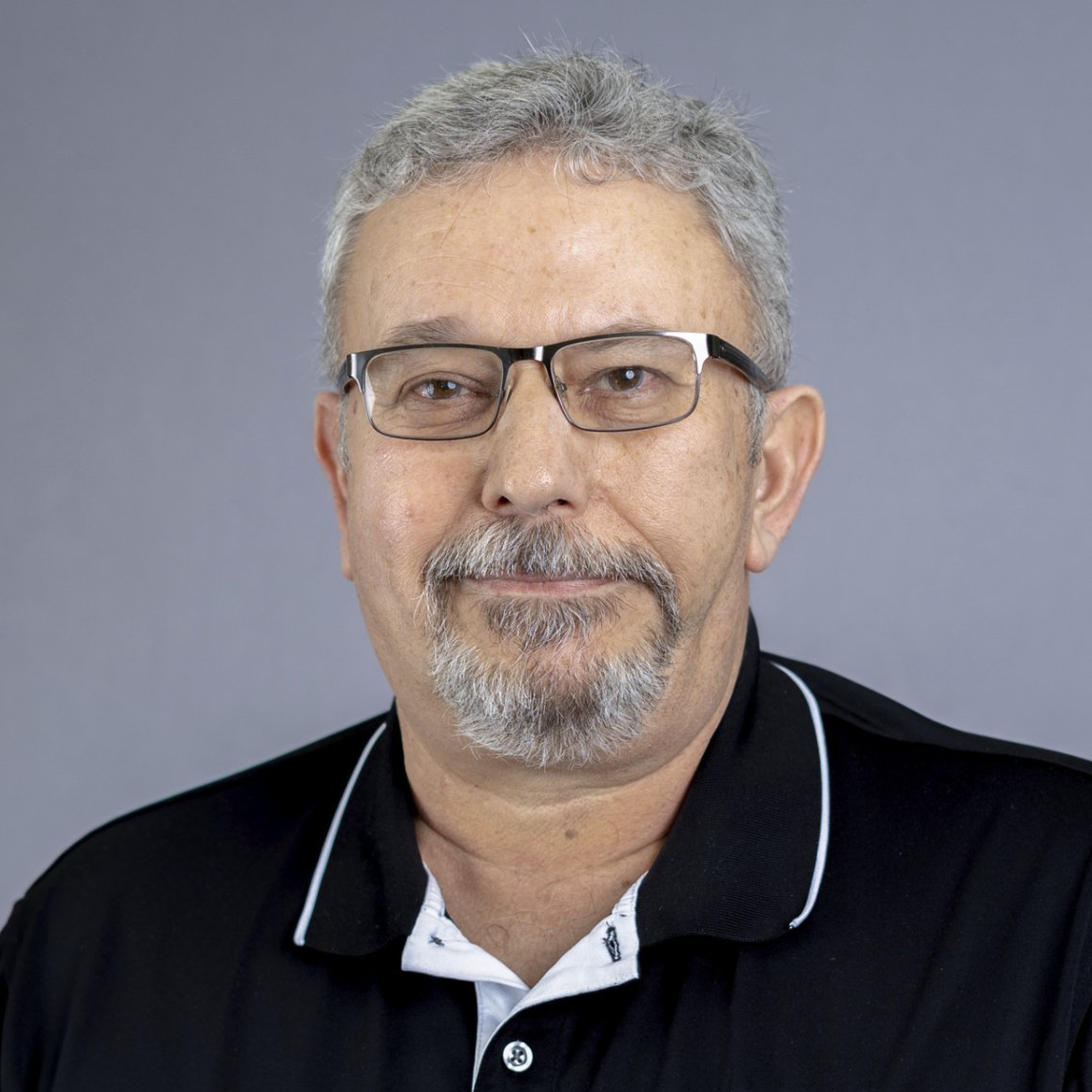 A man with glasses and a beard is wearing a black shirt.