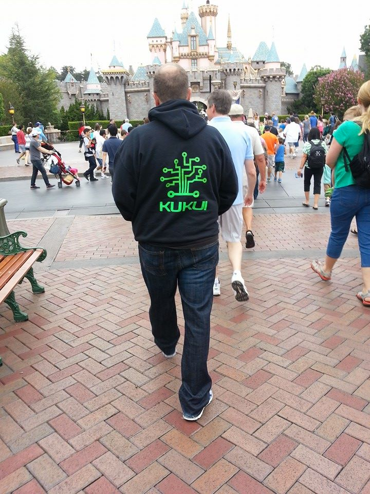 A man wearing a hoodie that says kukla walks in front of a castle