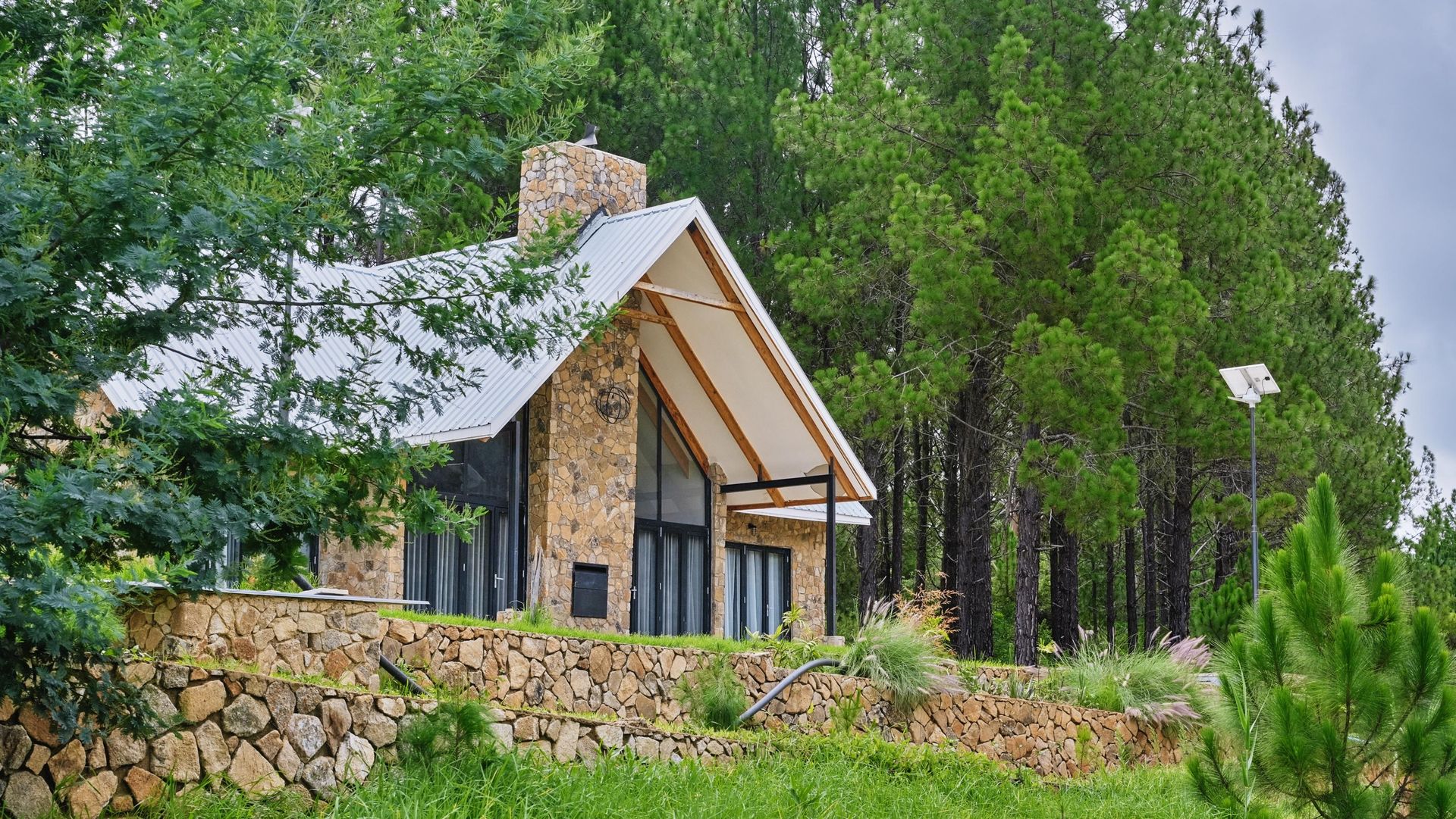 A small house is sitting on top of a hill in the middle of a forest.