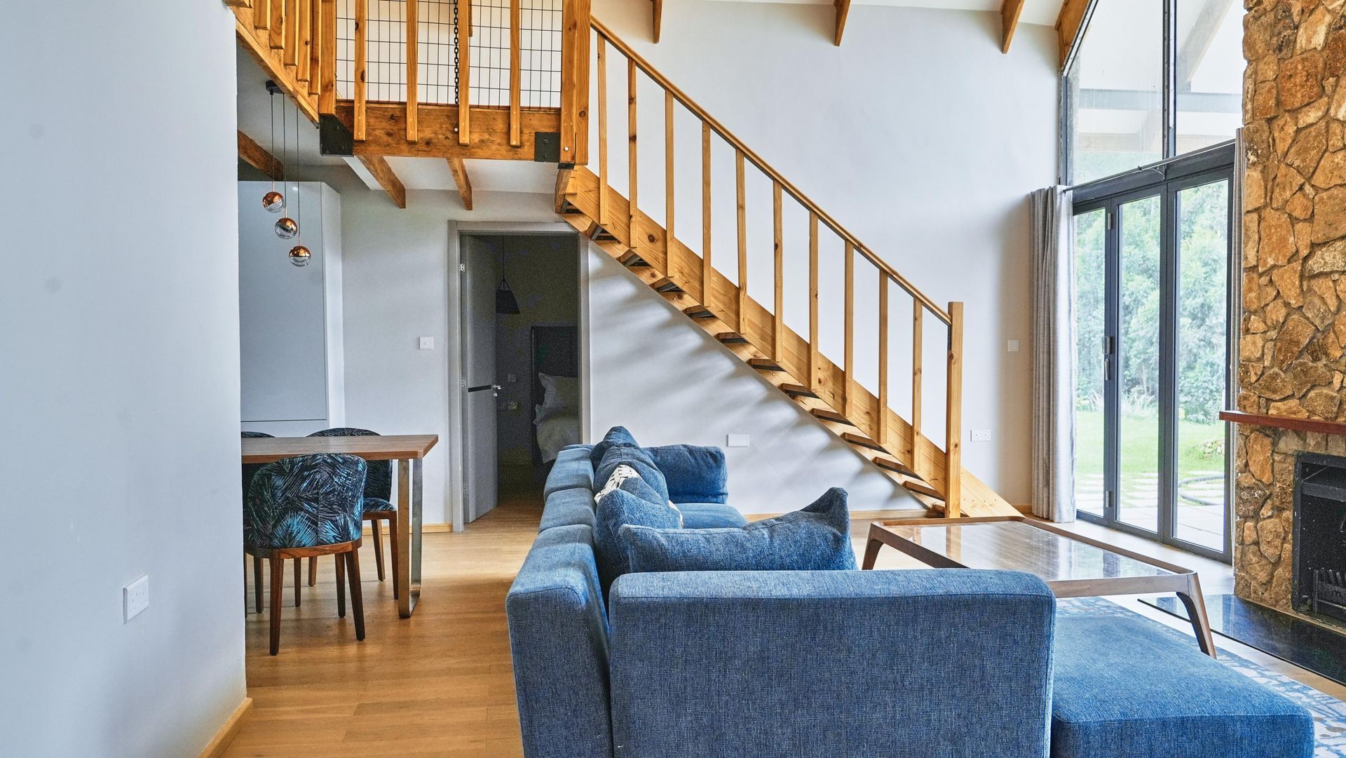 A living room with a blue couch and stairs leading up to the second floor.