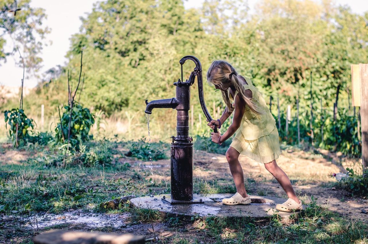 A little girl is pumping water from a well.