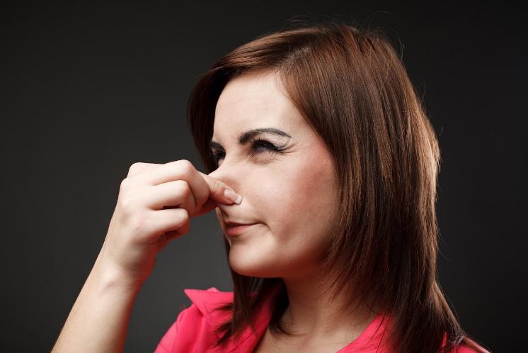 A woman is holding her nose because of a bad smell.