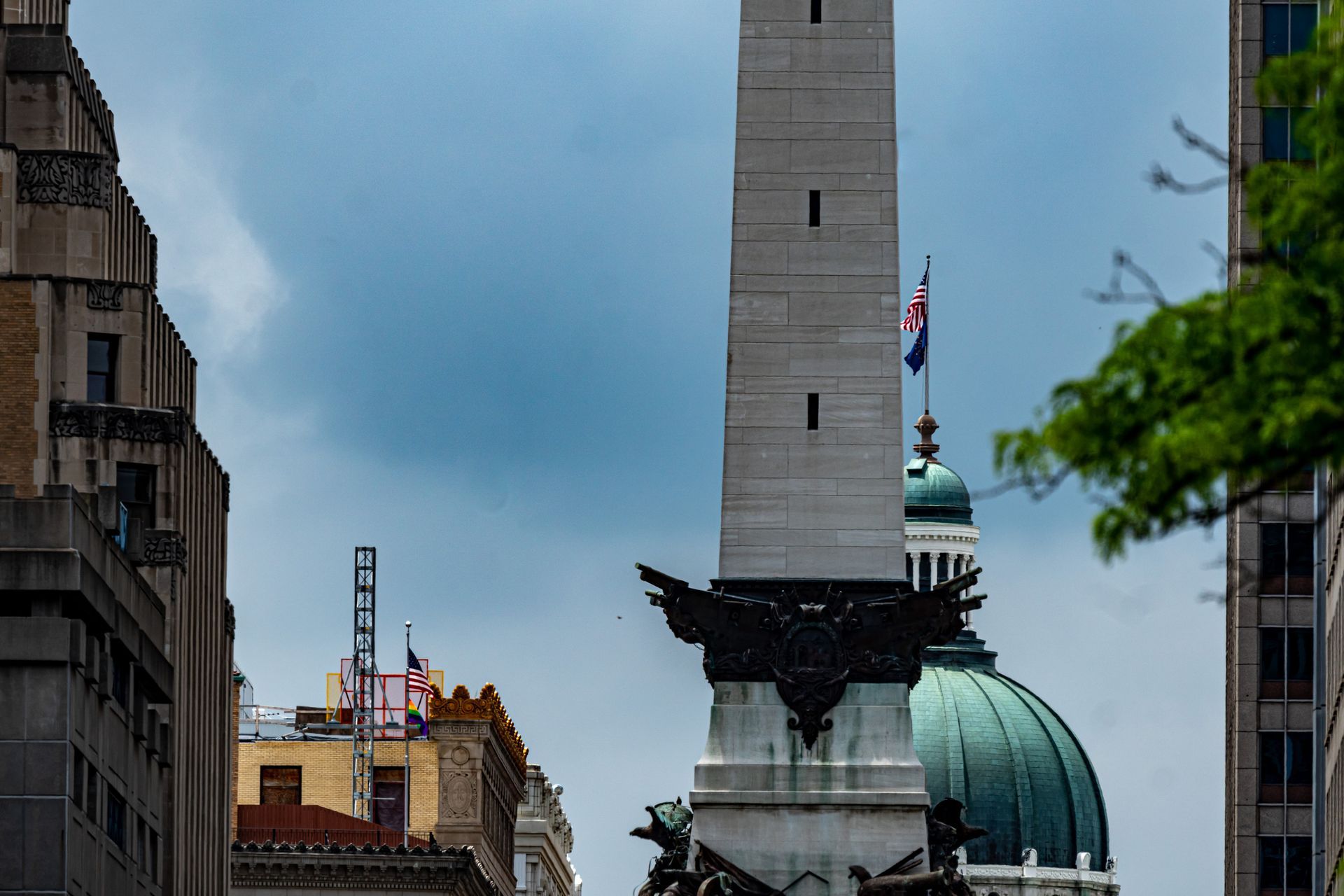 A large obelisk in the middle of a city surrounded by buildings.