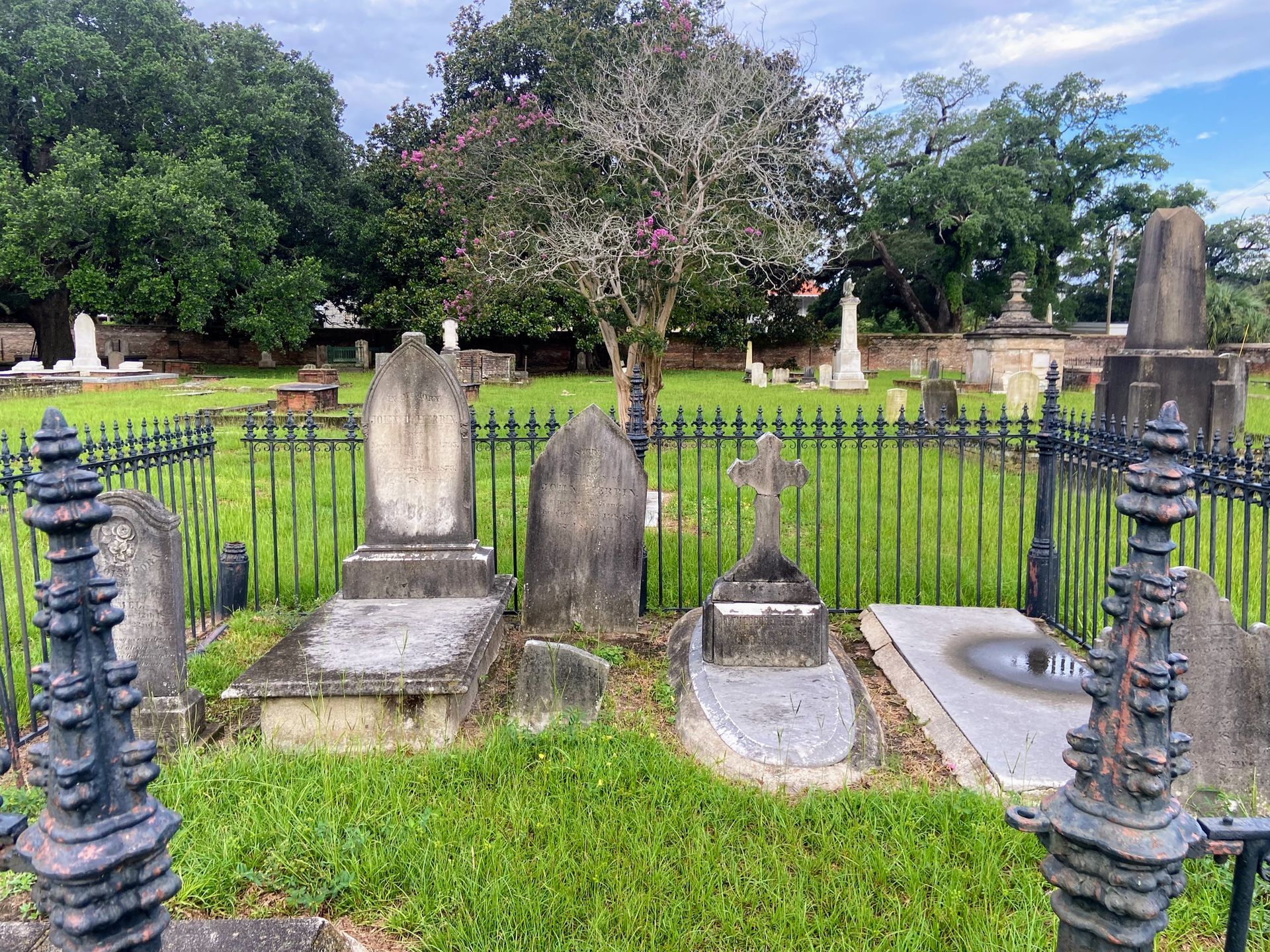 A cemetery with a fence and graves in the grass.