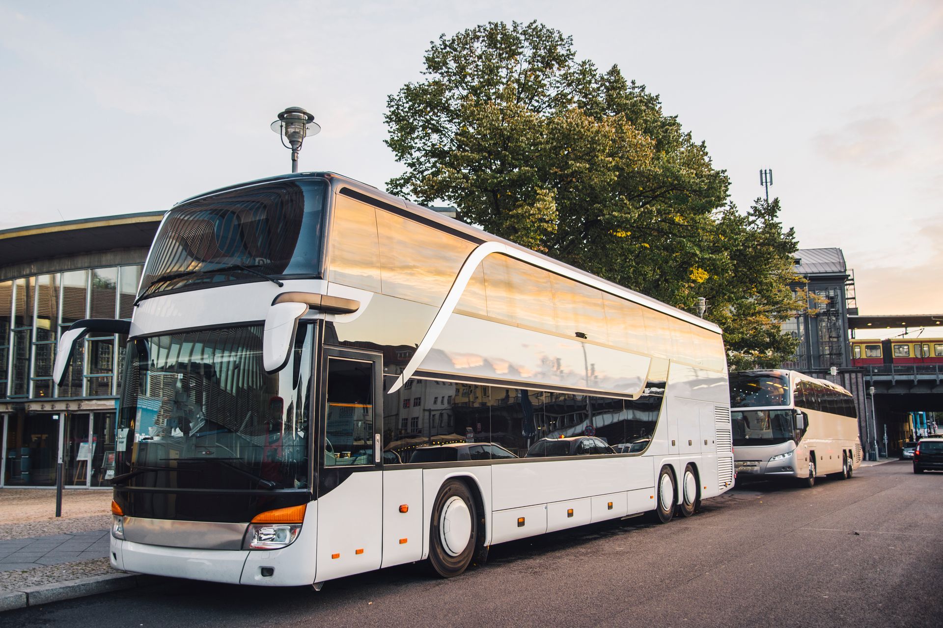 A white double decker bus is parked in front of a building.