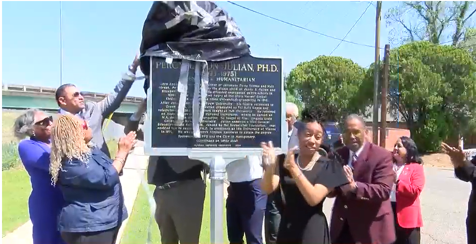 A group of people are standing around a historical marker.