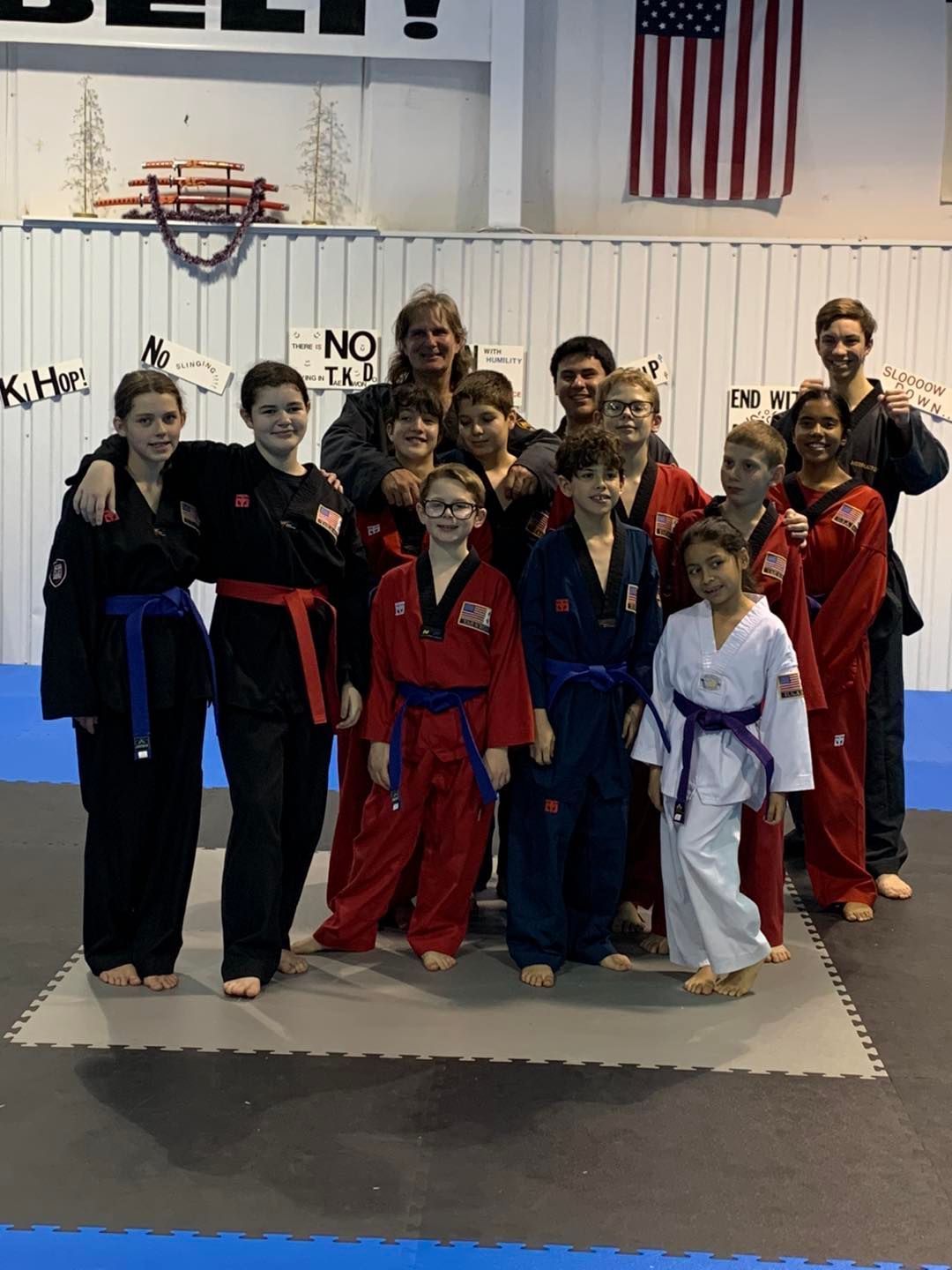 A group of kids in karate uniforms pose for a picture