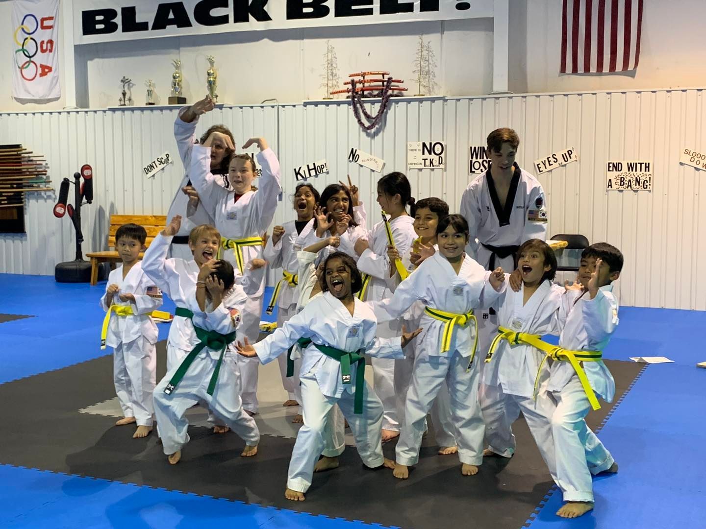 A group of children in karate uniforms are posing for a picture in a gym.
