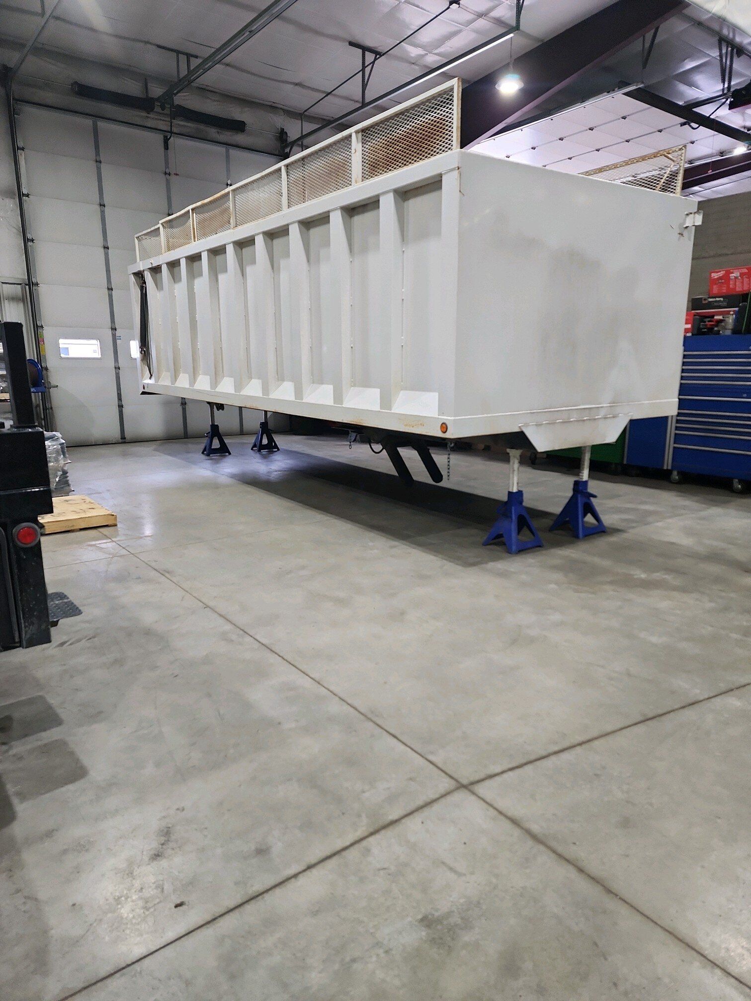 A white dumpster is sitting on top of a concrete floor in a garage.