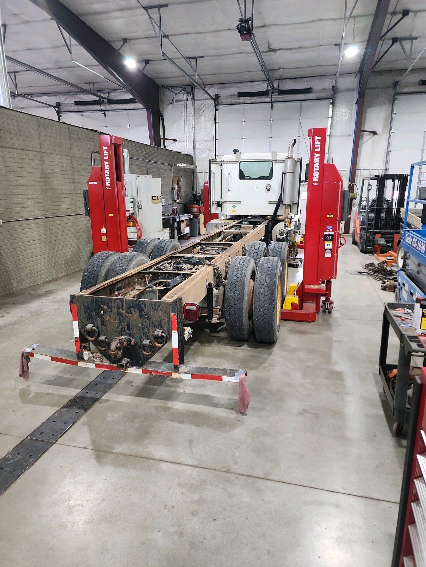 A semi truck is being repaired in a garage.