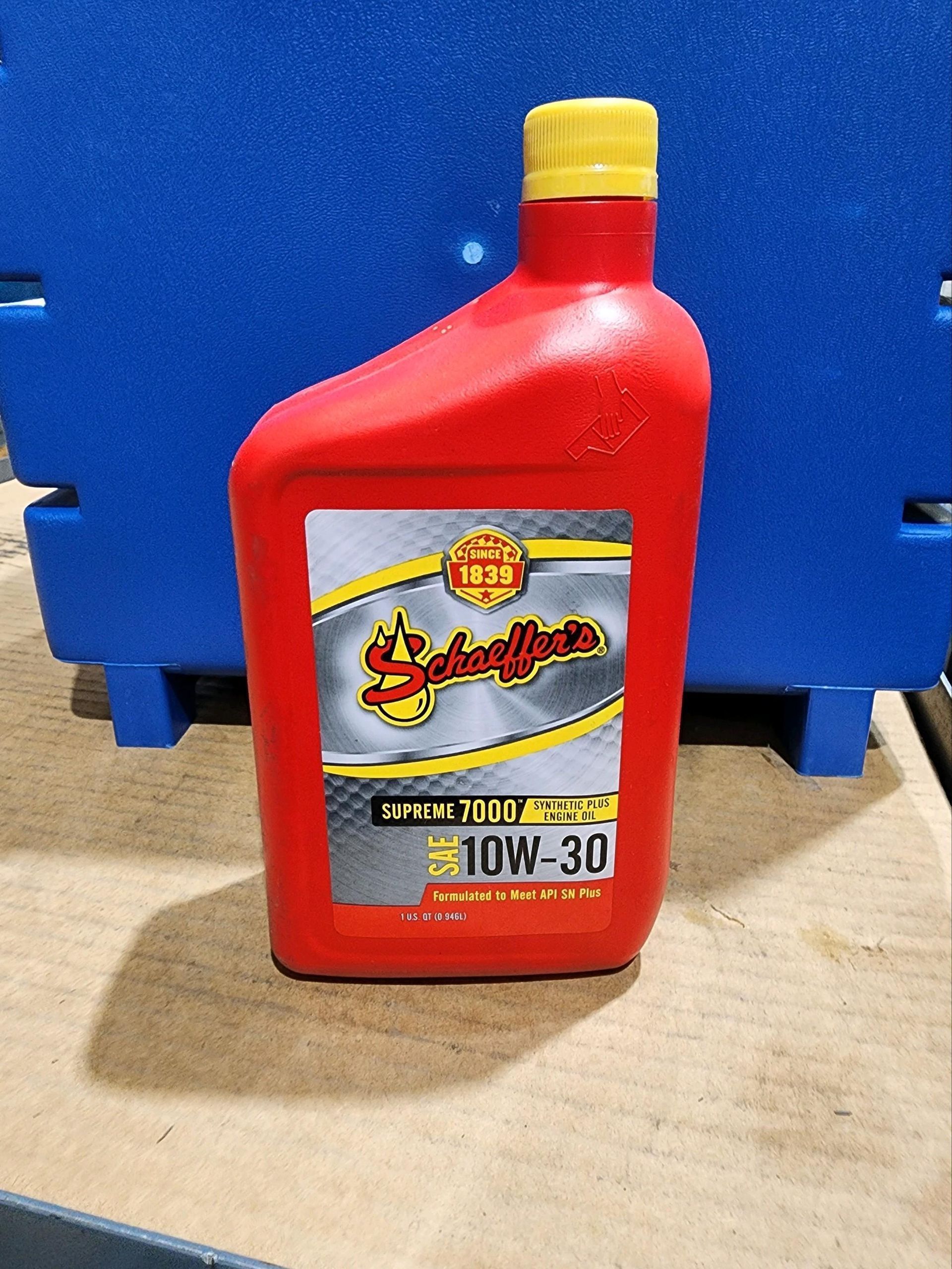 A bottle of oil is sitting on a table next to a blue box.