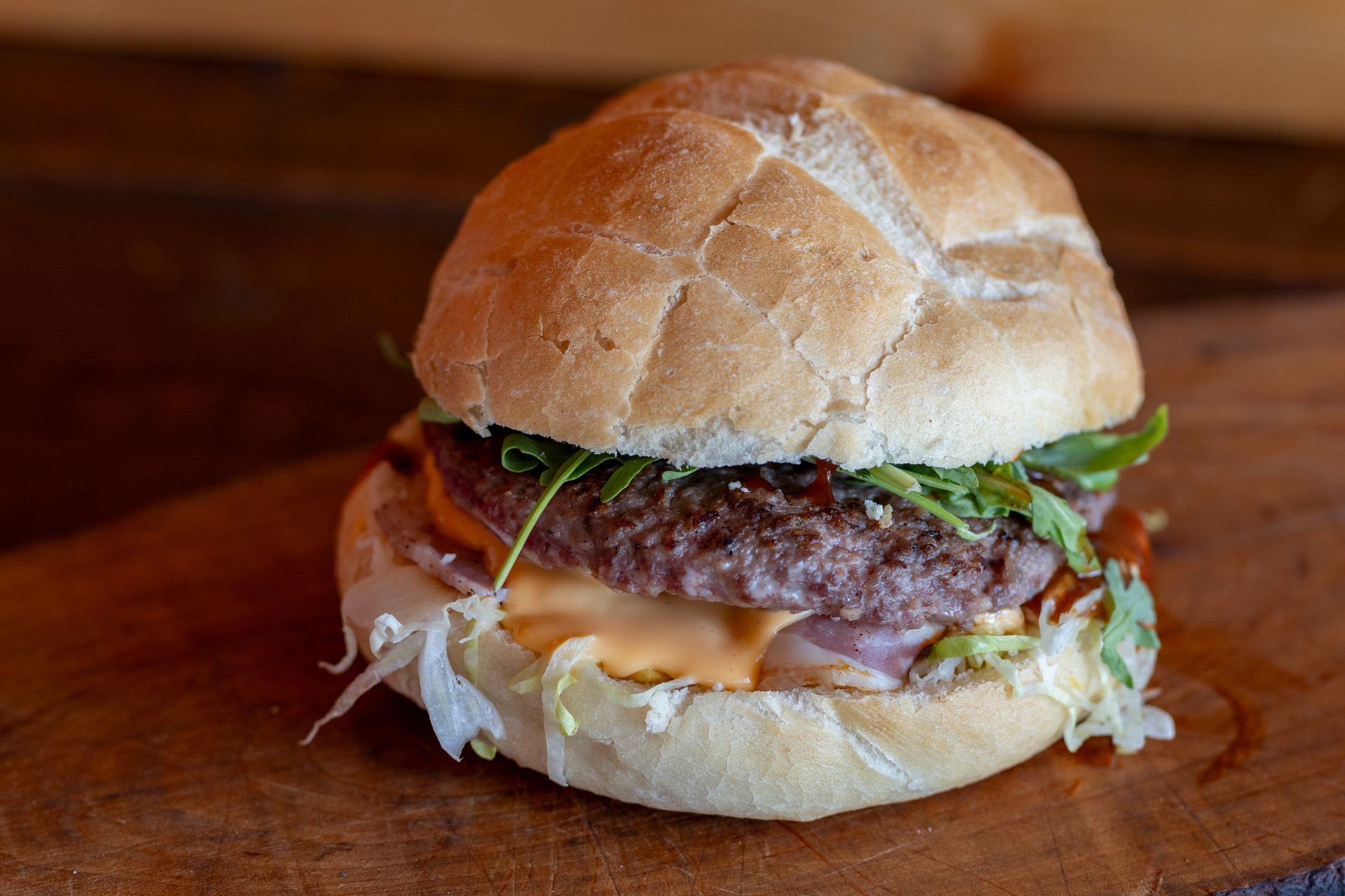 Un primo piano di un hamburger su un panino su un tavolo di legno.