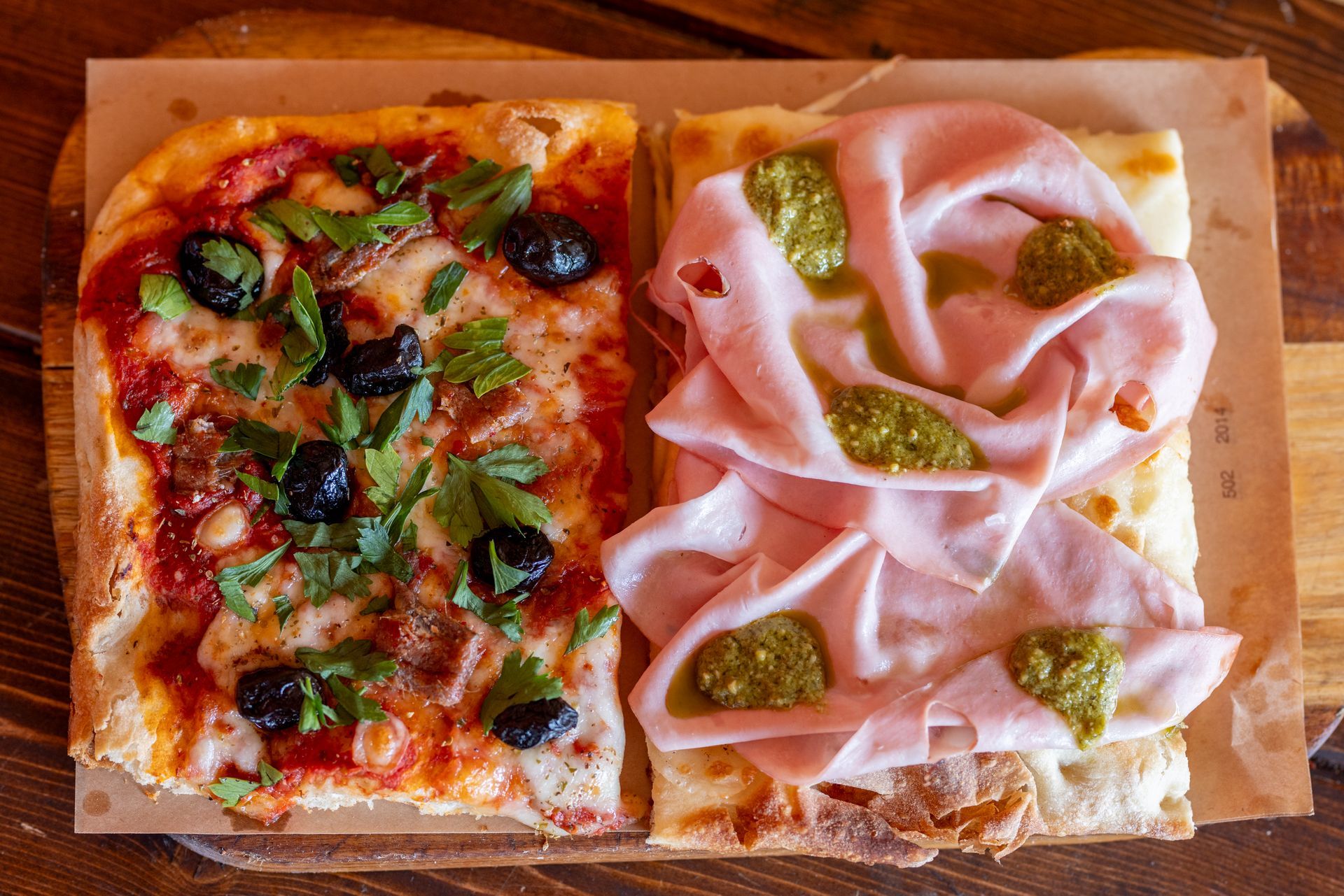 Due pizze con condimenti diversi sono su un tagliere di legno.
