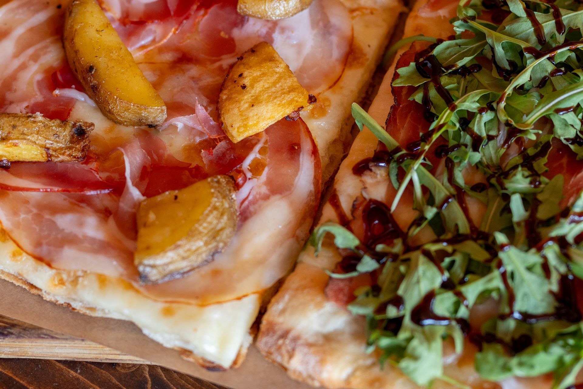 Due fette di pizza sono appoggiate su un tavolo di legno.