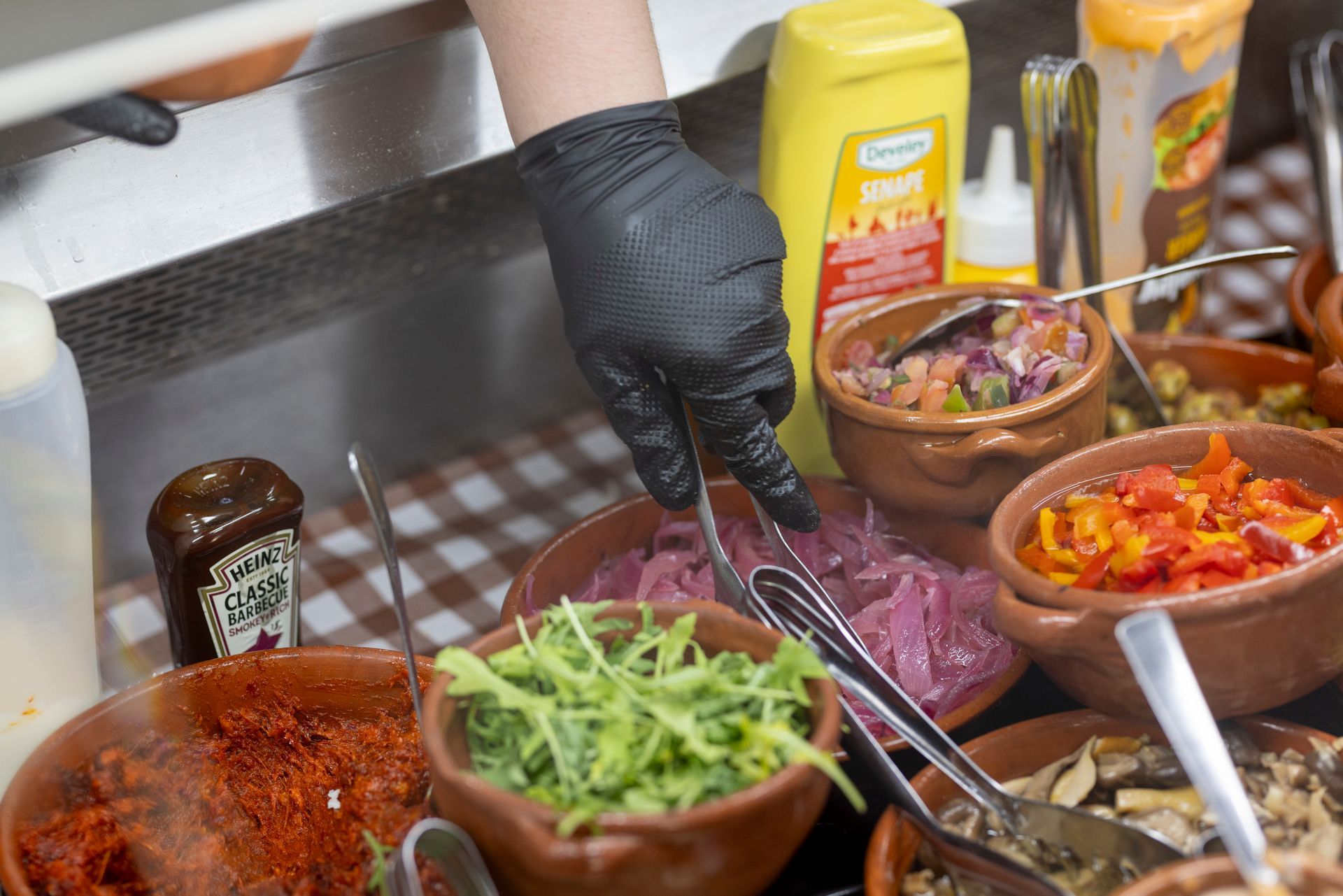 Una persona sta preparando il cibo in cucina con ciotole di verdure e condimenti.