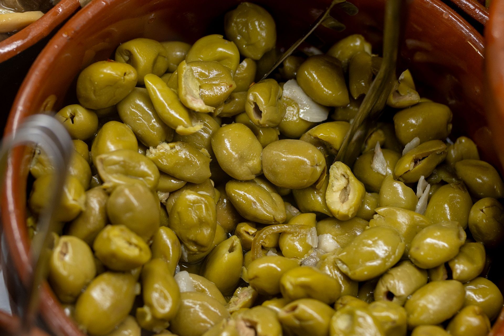 Una ciotola di olive verdi con un cucchiaio dentro