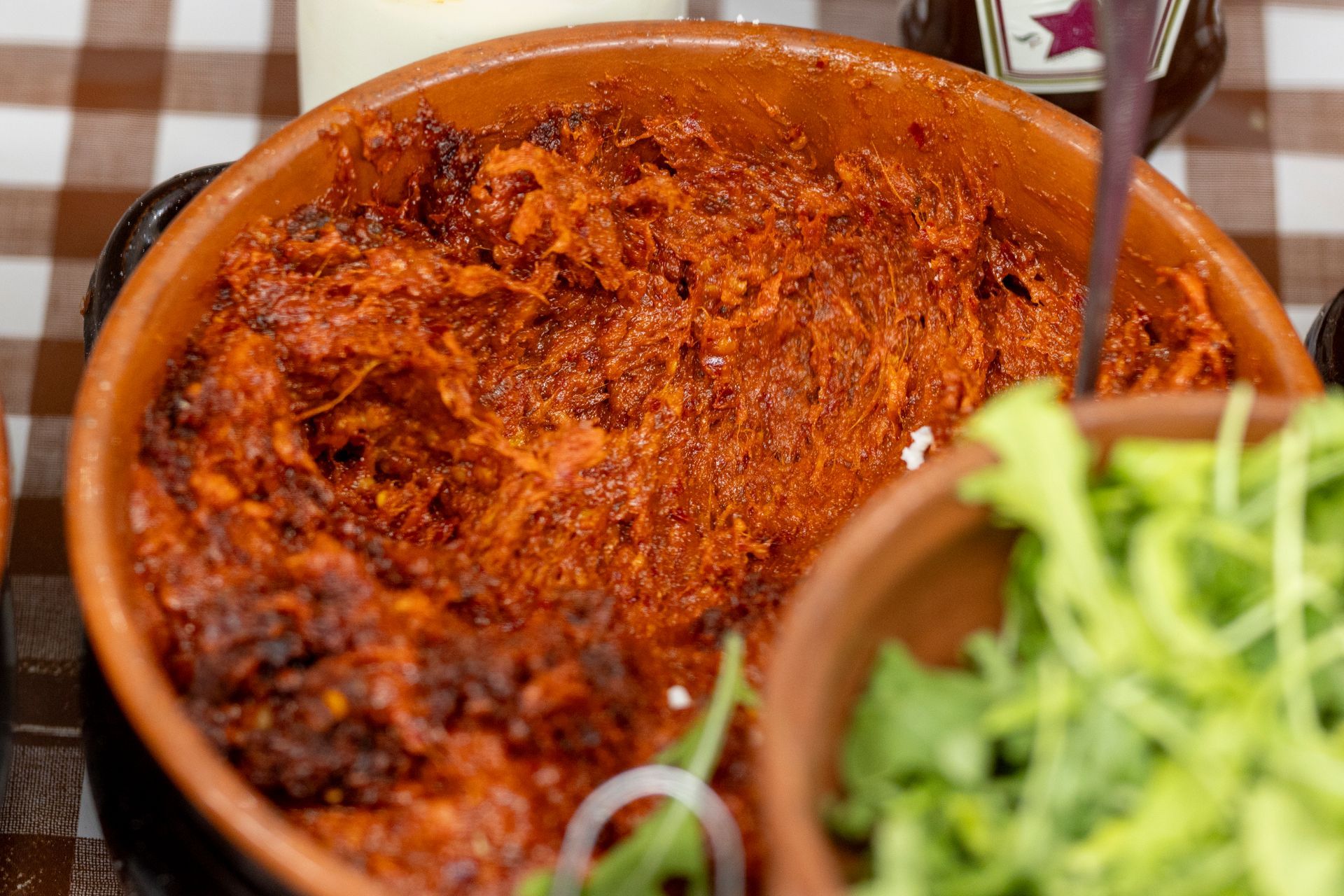 Una ciotola di cibo è appoggiata su un tavolo accanto a una bottiglia di ketchup.