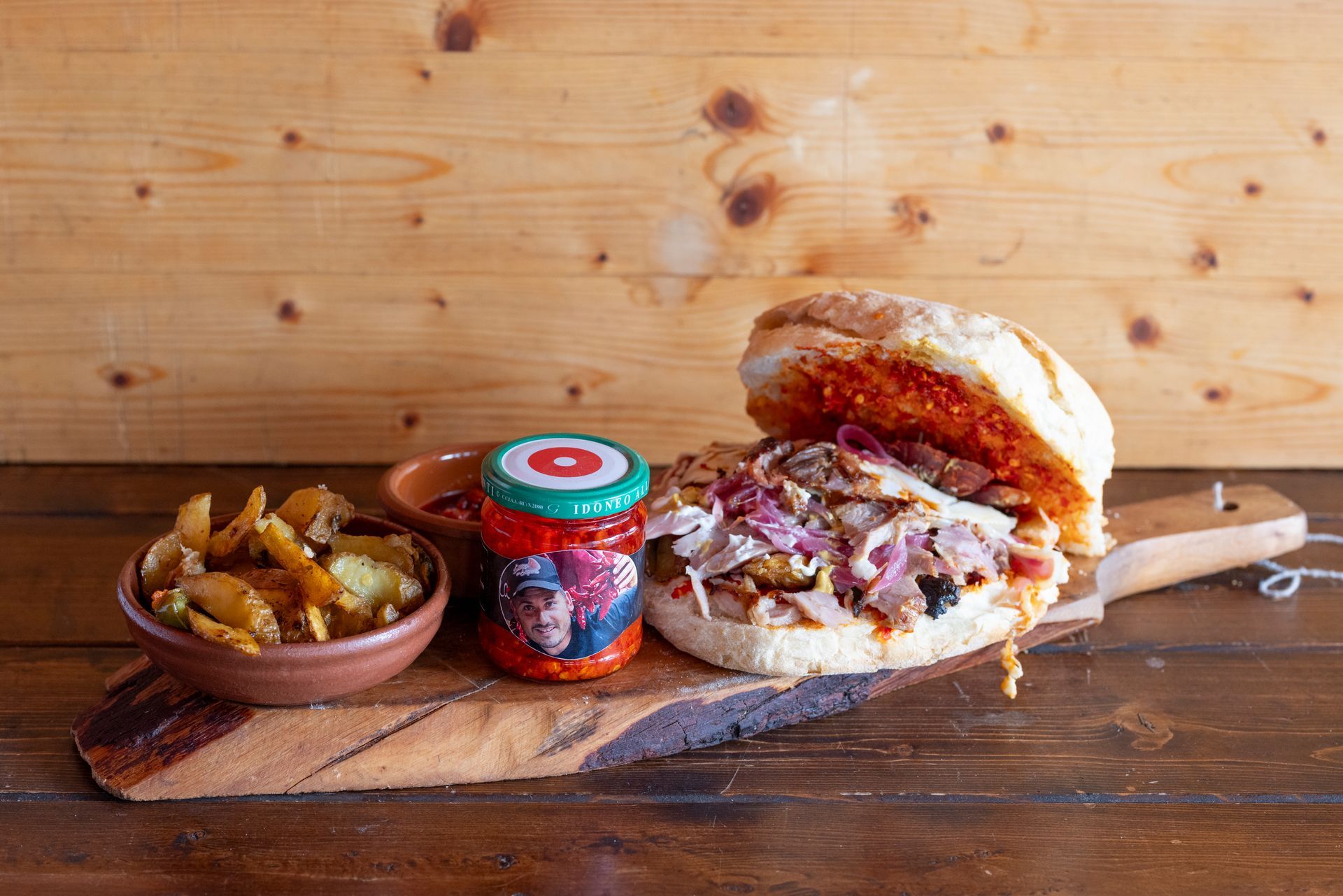 Un panino e delle patatine fritte sono su un tagliere di legno.