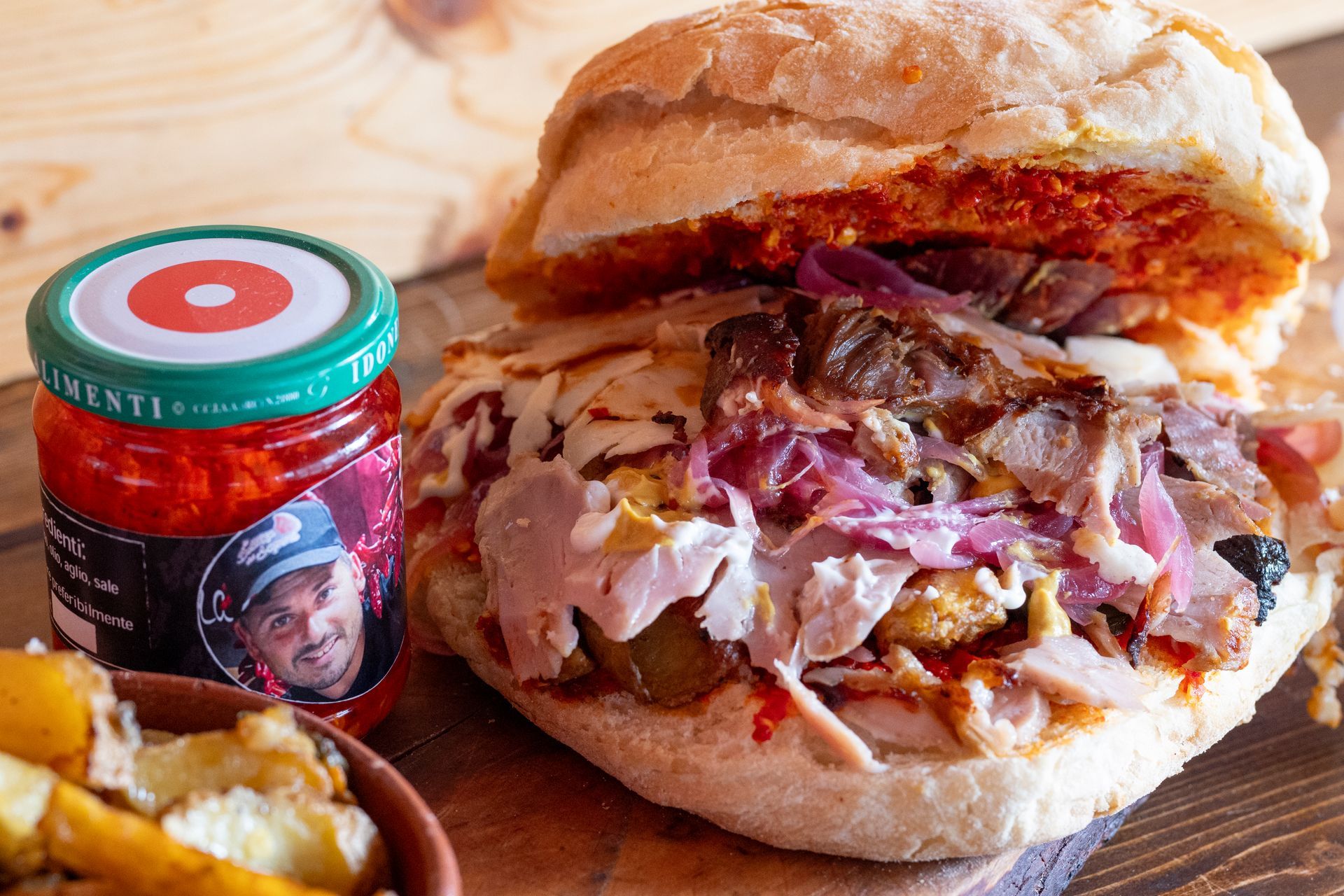 Un panino e un barattolo di sottaceti sono su un tavolo di legno.