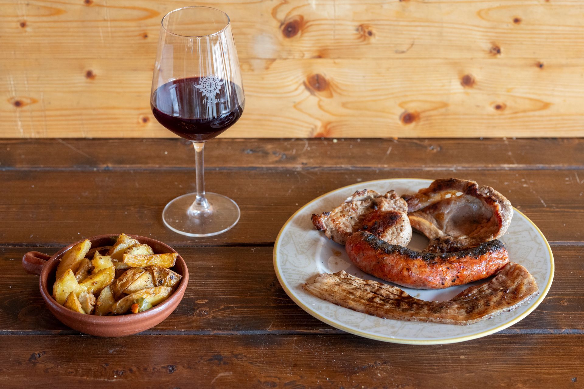 Un piatto di cibo e un bicchiere di vino su un tavolo di legno.