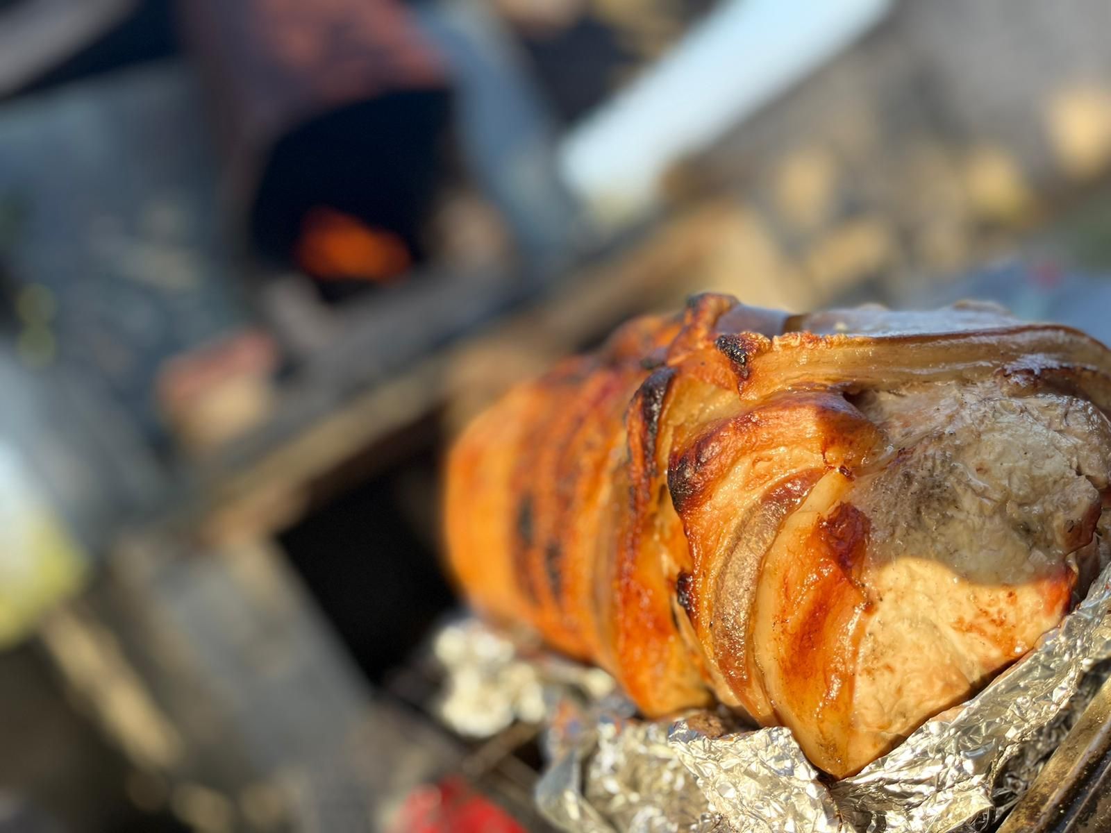 Primo piano di un pezzo di carne avvolto in un foglio di stagnola su una griglia.