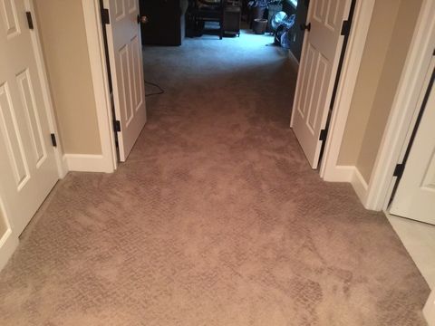 Hallway with beige carpet, flanked by two closed white doors with black hardware, leading to a room.