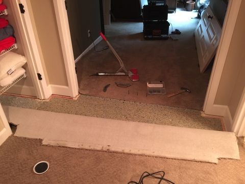Carpet being installed in a doorway; tools and carpet strip in view.