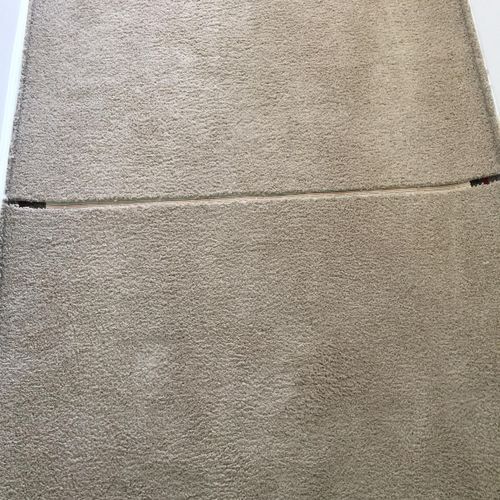 Beige carpet with a horizontal seam and two dark rectangles.