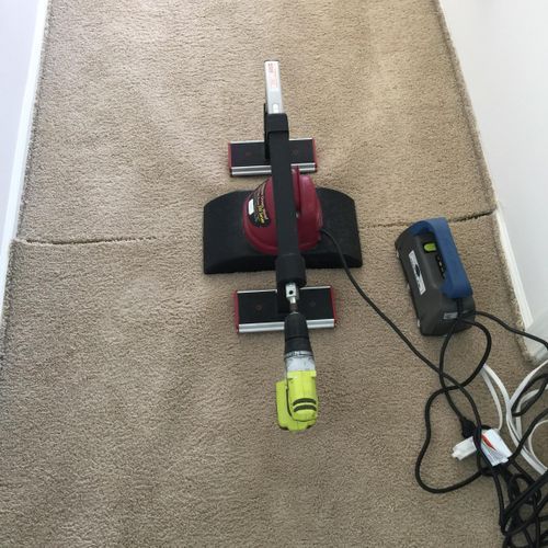Carpet cleaning tool with attached drill connected to a power supply.