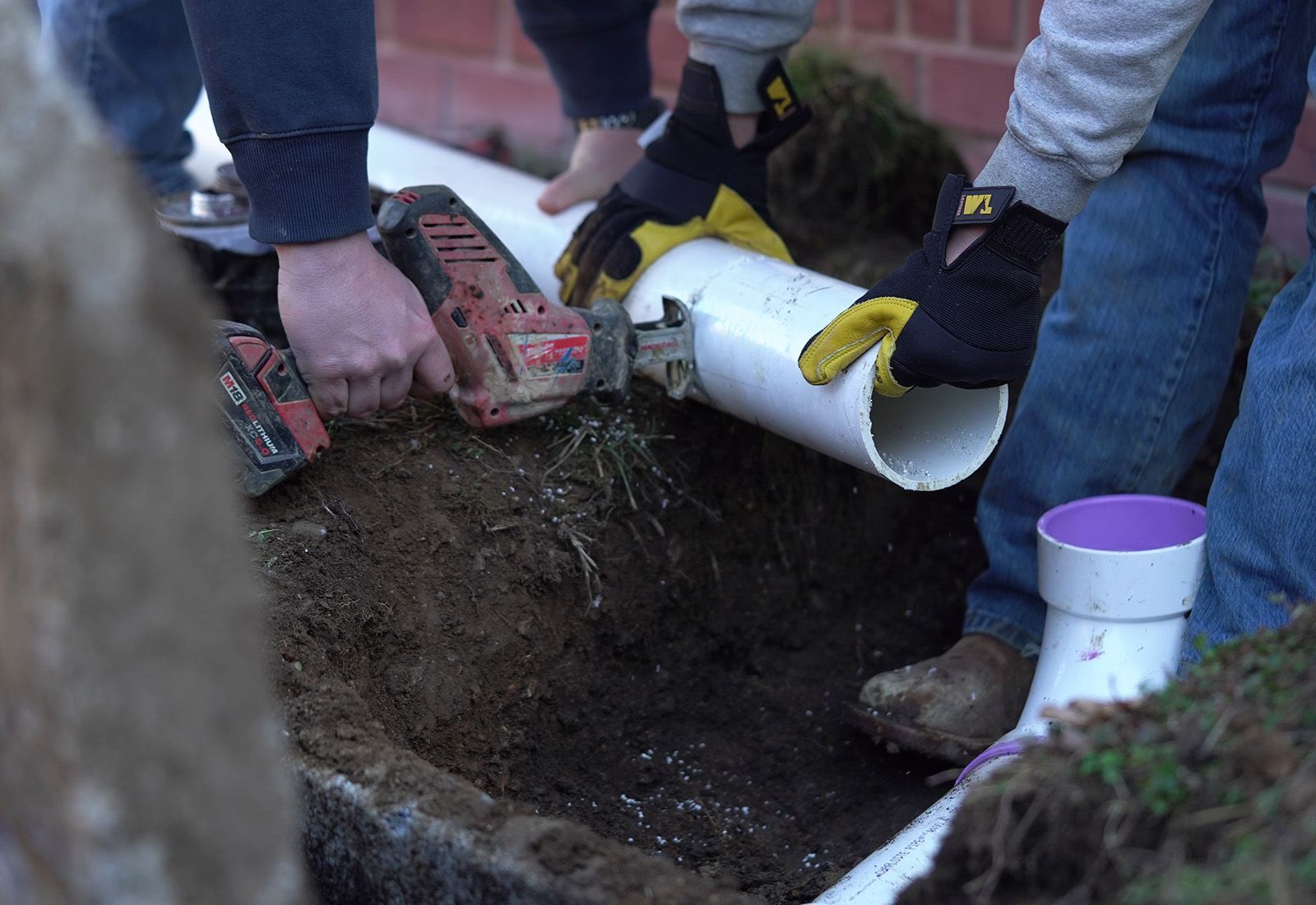two employees repairing an inlet pipe for a septic tank