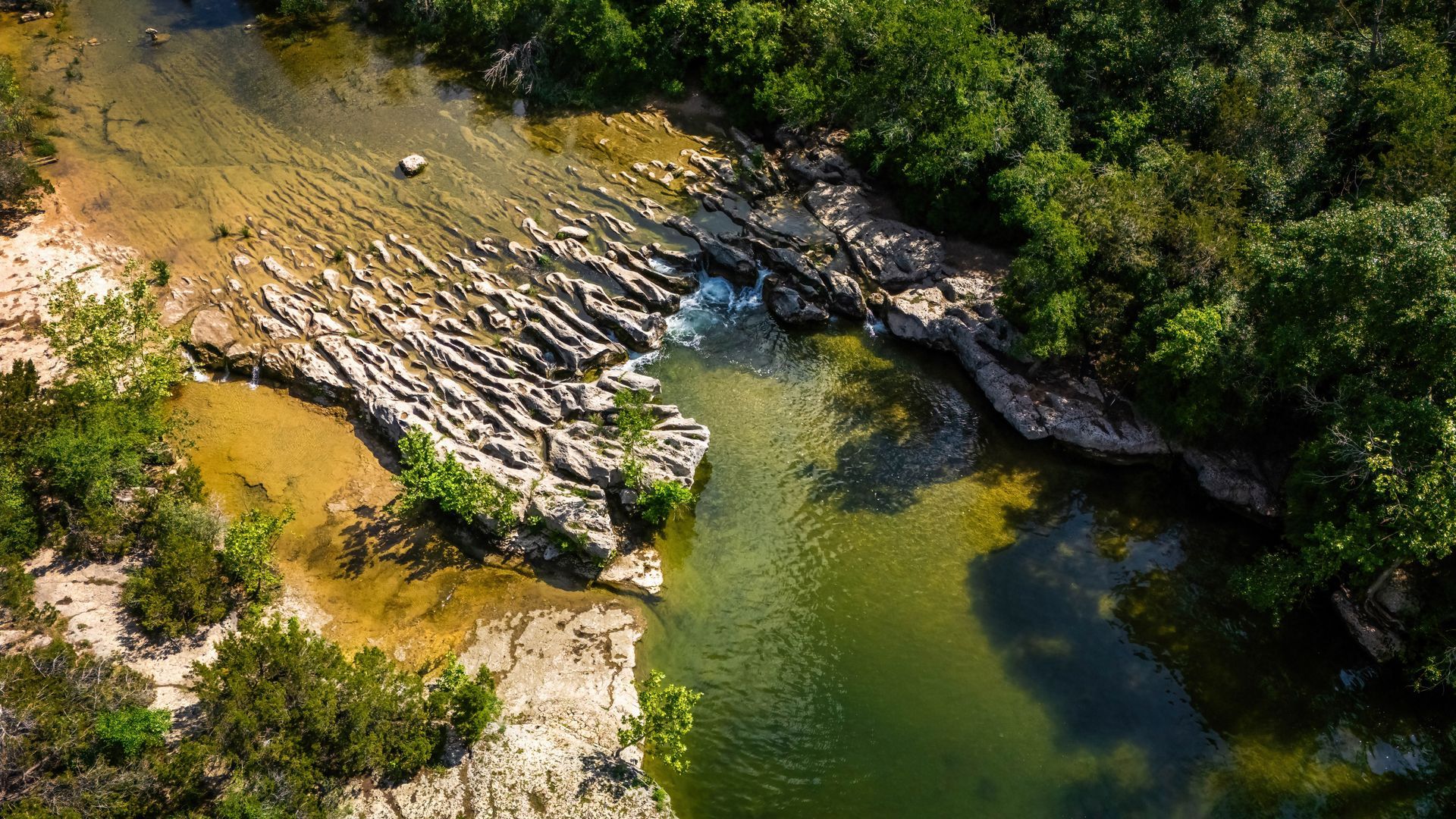 An aerial view of a river surrounded by trees and rocks.