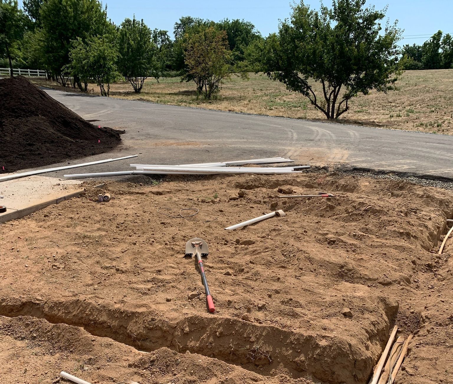 A shovel is sitting in the middle of a dirt field.